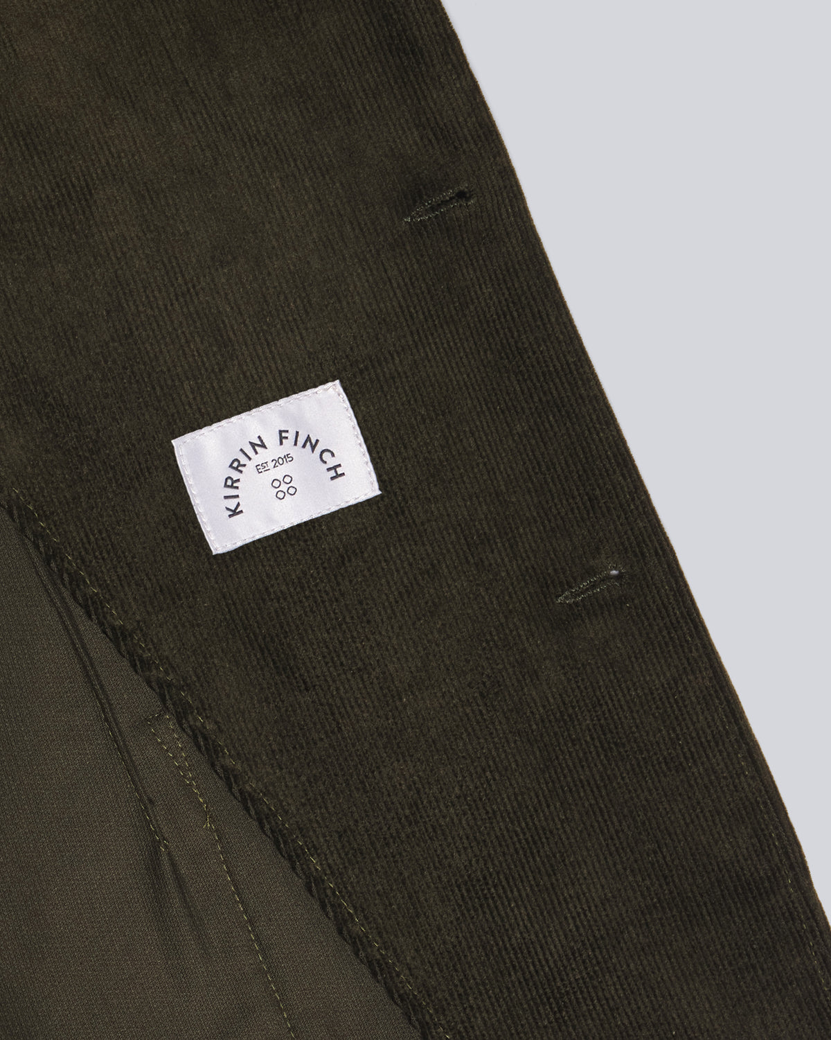 Close-up of dark olive corduroy fabric with a white sewn-in inner label. Color: Pine