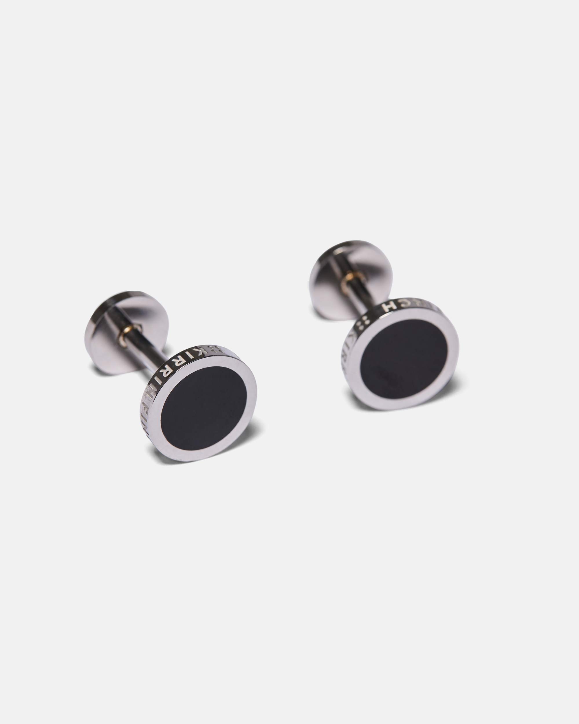 Pair of silver cufflinks with black centers on a light gray background made by Kirrin Finch.