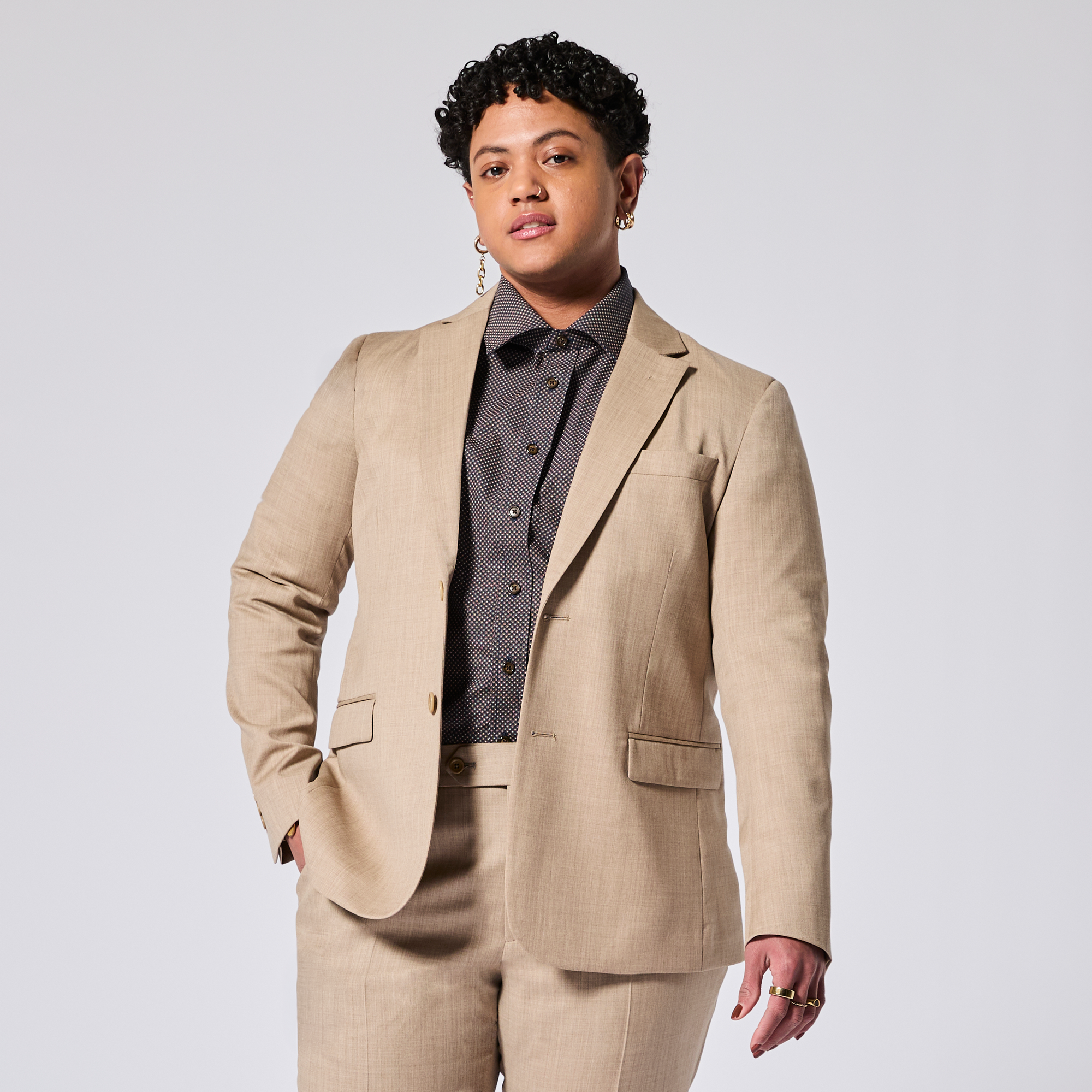 Person wearing a beige suit with a button-up shirt on a white background. Color: Desert