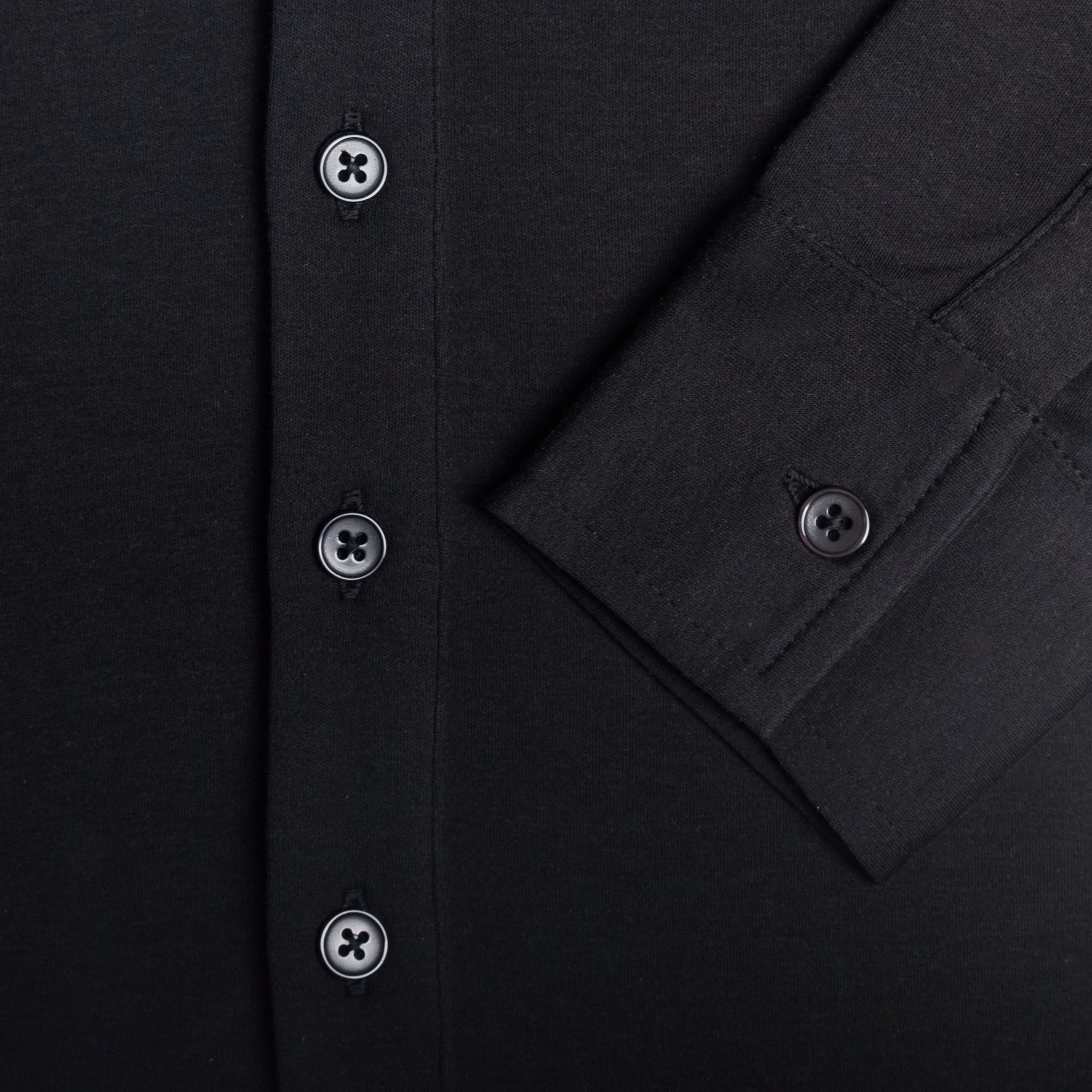 Close-up of a black shirt with button details. Color: Black