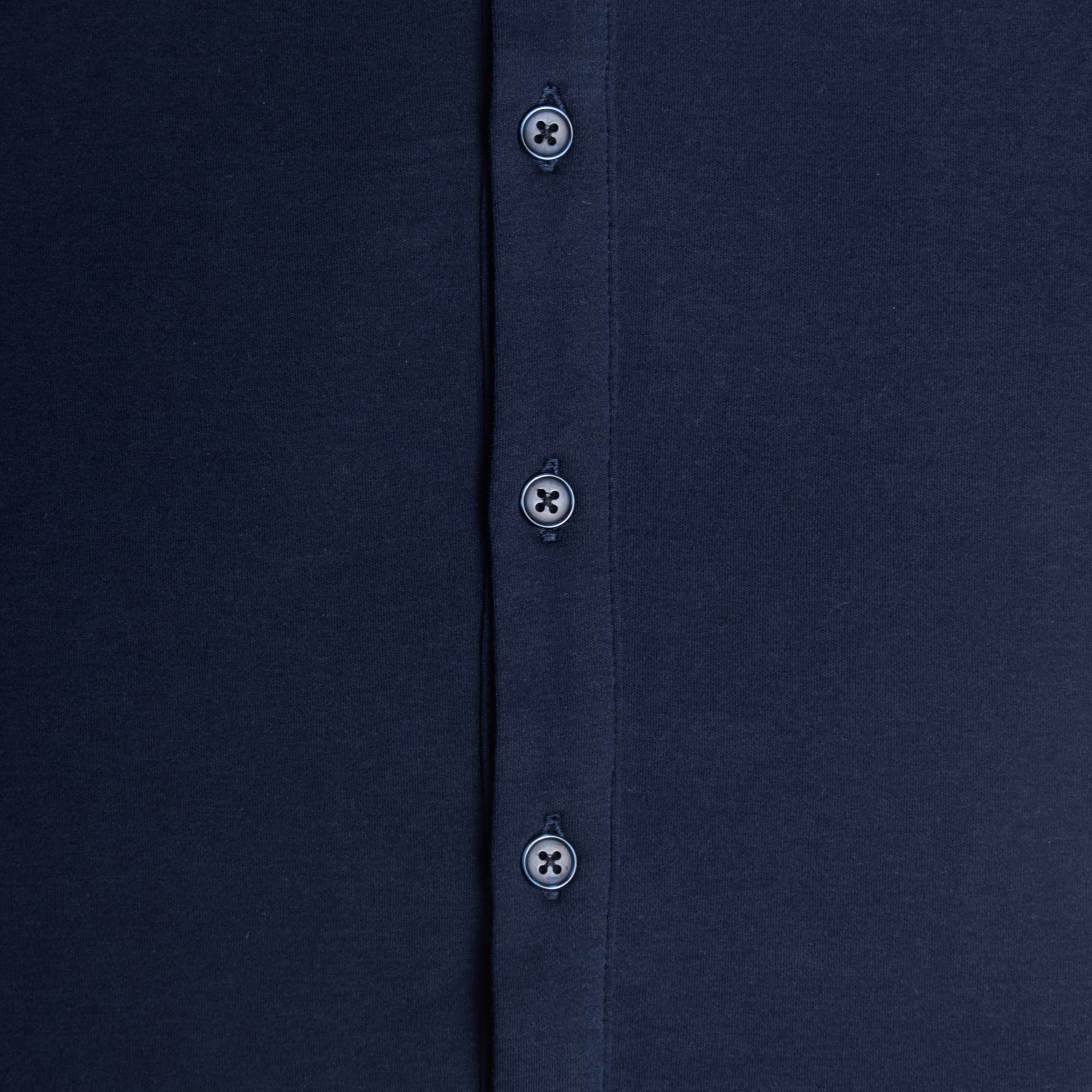 Close-up of a navy shirt with buttons on a plain background. Color: Navy