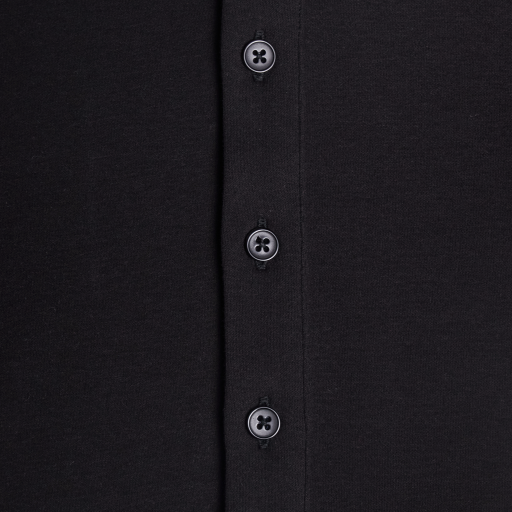 Close-up of a black shirt with buttons on a plain background. Color: Black