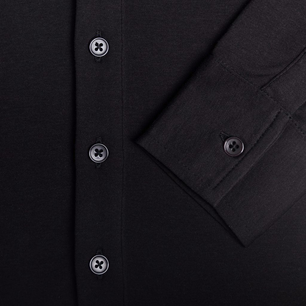 Close-up of a black shirt with button details. Color: Black