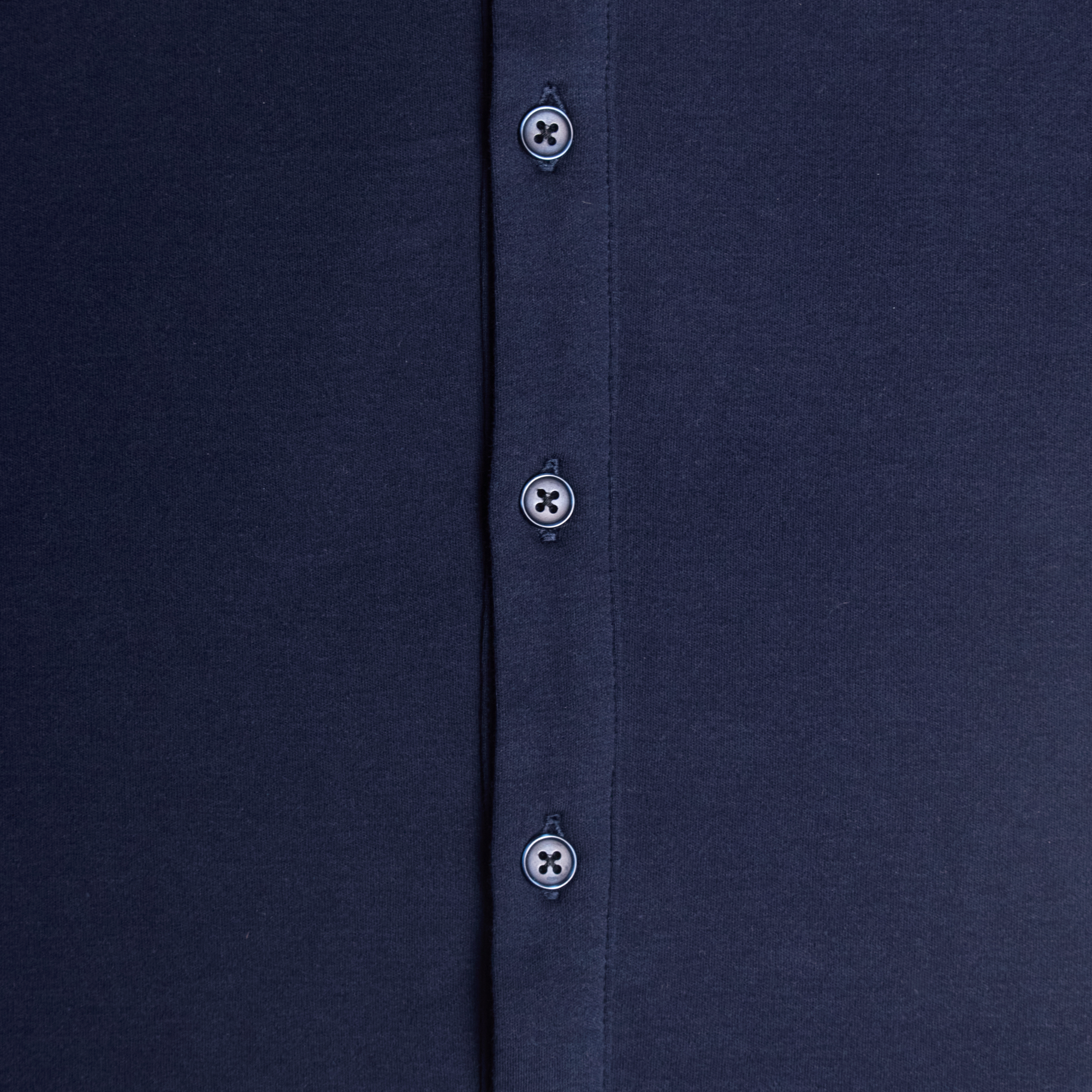 Close-up of a navy shirt with buttons on a plain background. Color: Navy