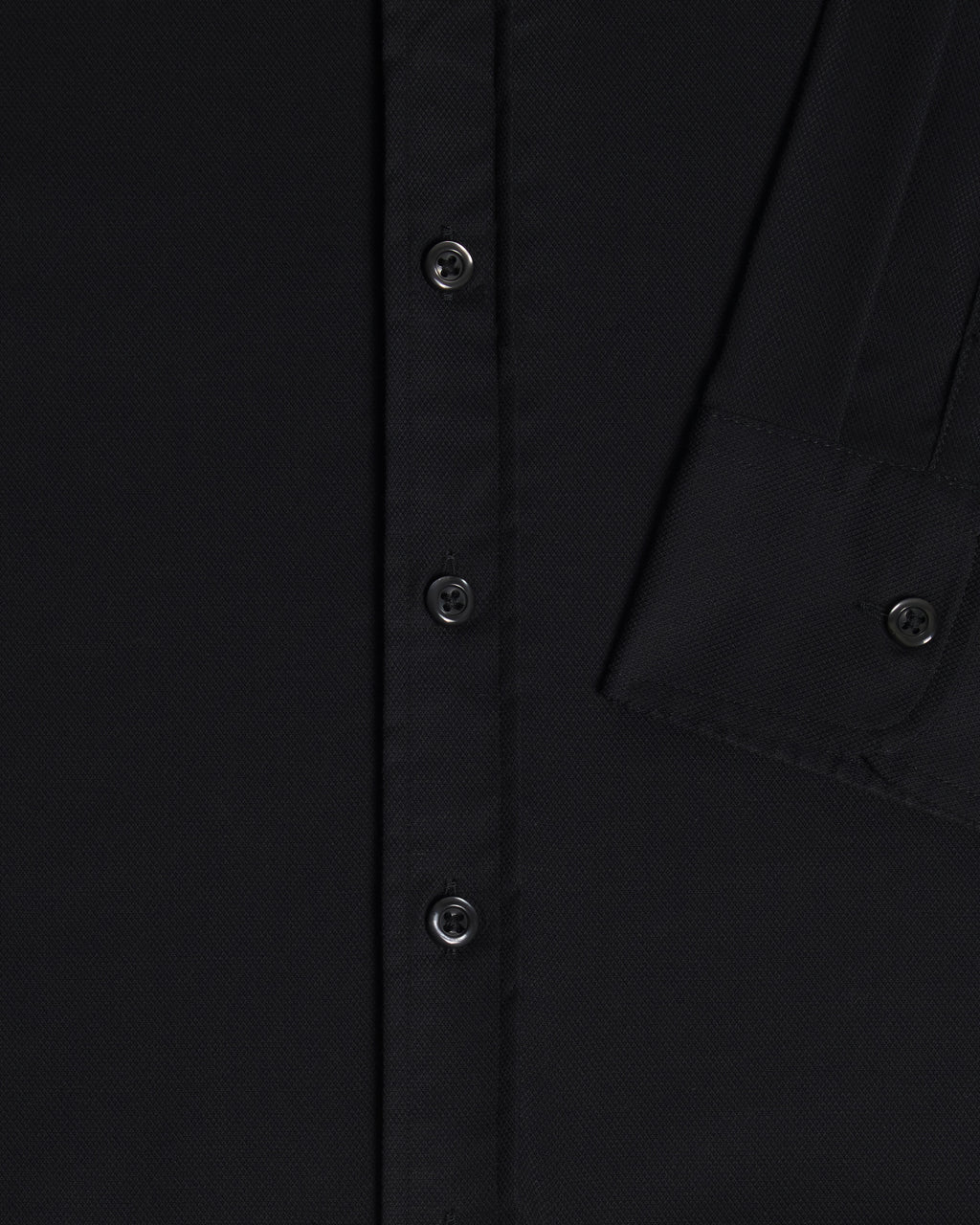 Close-up of a black button-up shirt showing the front button placket, fabric texture, and sleeve cuff details. Color: Black