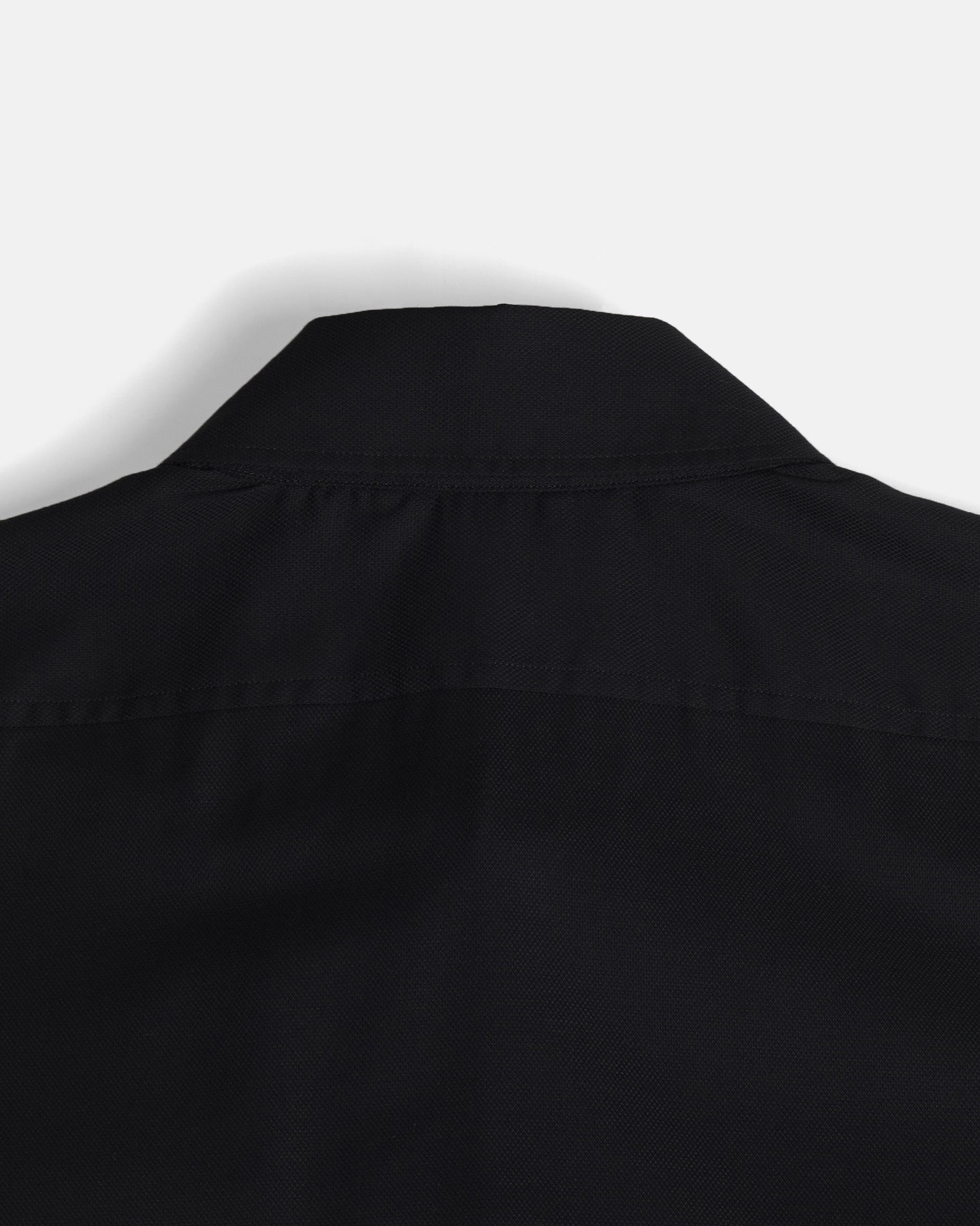 Close-up of the collar and shoulder area of a black button-down shirt taken from behind. Color: Black