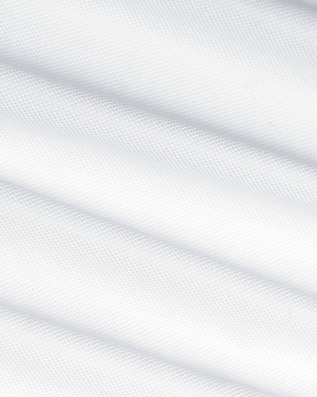 A close-up of white textured fabric with soft diagonal folds and a fine woven pattern. Color: White