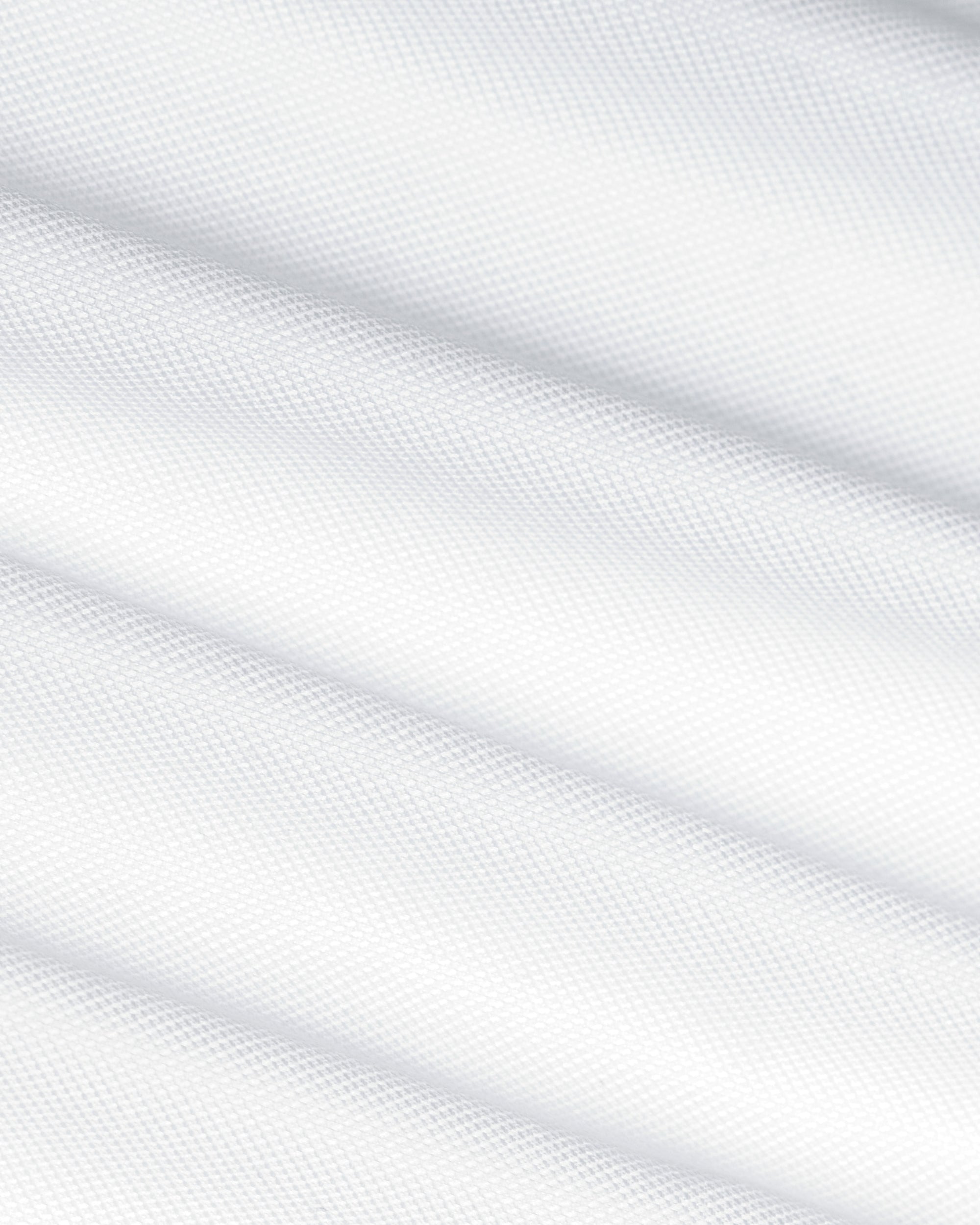 A close-up of white textured fabric with soft diagonal folds and a fine woven pattern. Color: White