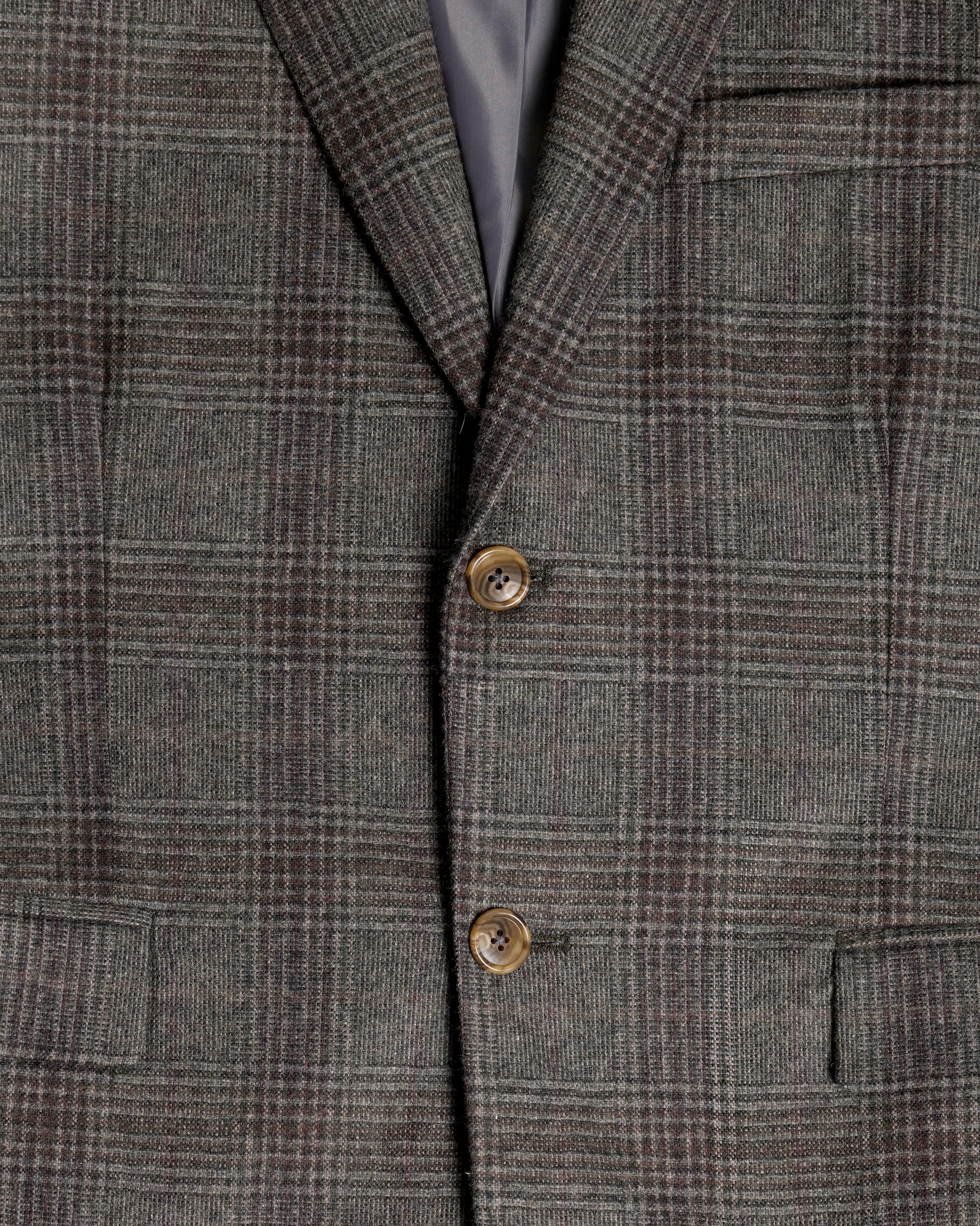 Close-up of a gray and brown plaid tweed blazer jacket, showing the fabric texture, two brown buttons, and a dark gray inner lining. Color: Earthen Glen Plaid
