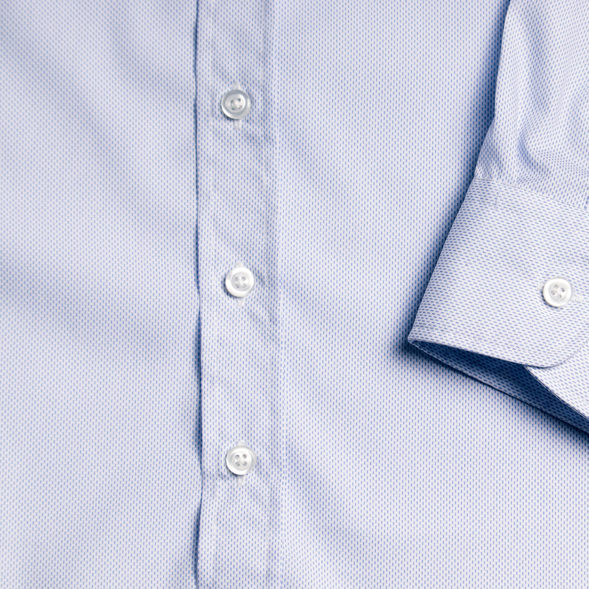 Close-up of the Microtally shirt with buttons and a rolled-up sleeve on a matching fabric background.  Color: Microtally