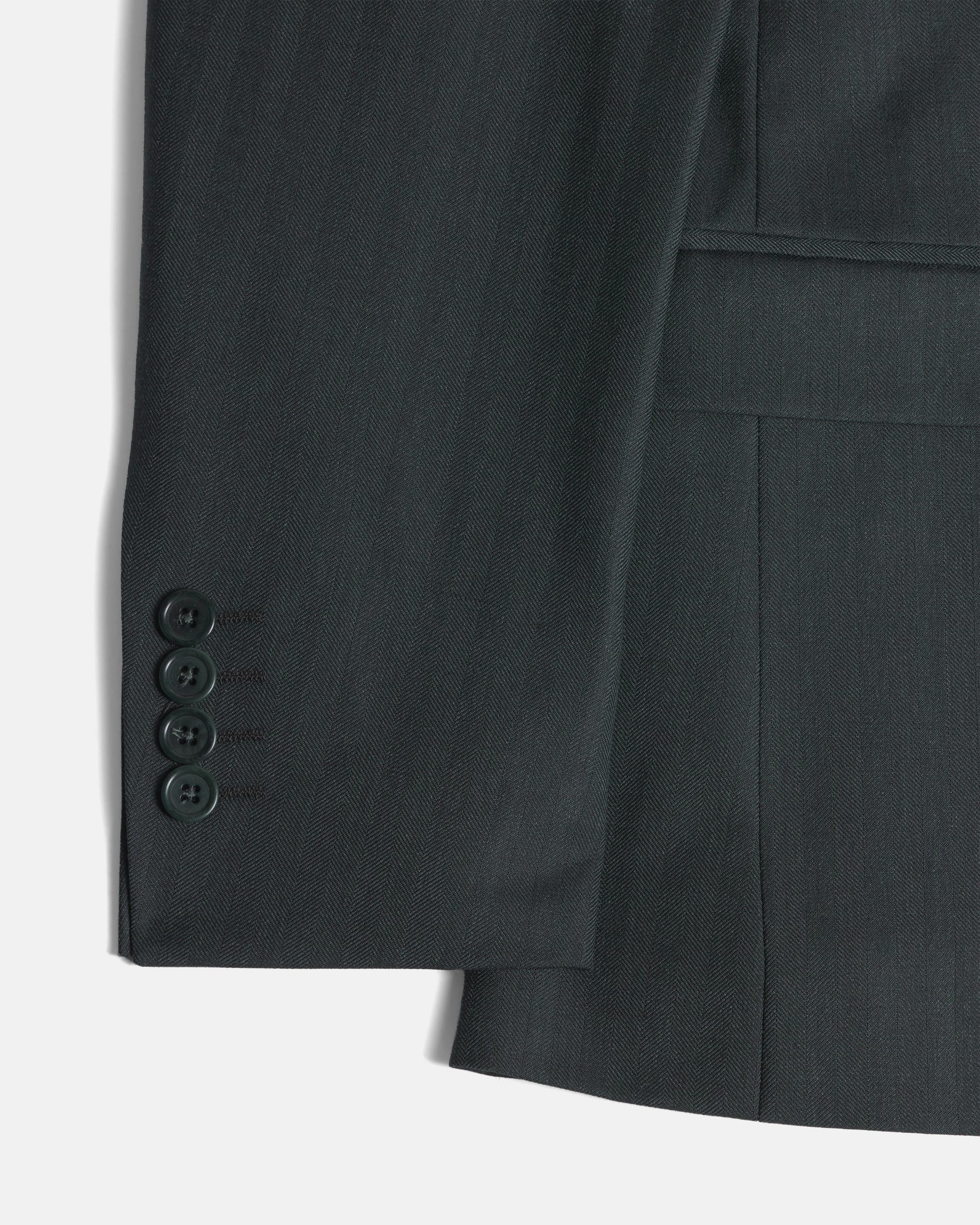 Close-up of a dark green suit jacket showing the buttoned cuff. Color: Midnight Pine Herringbone