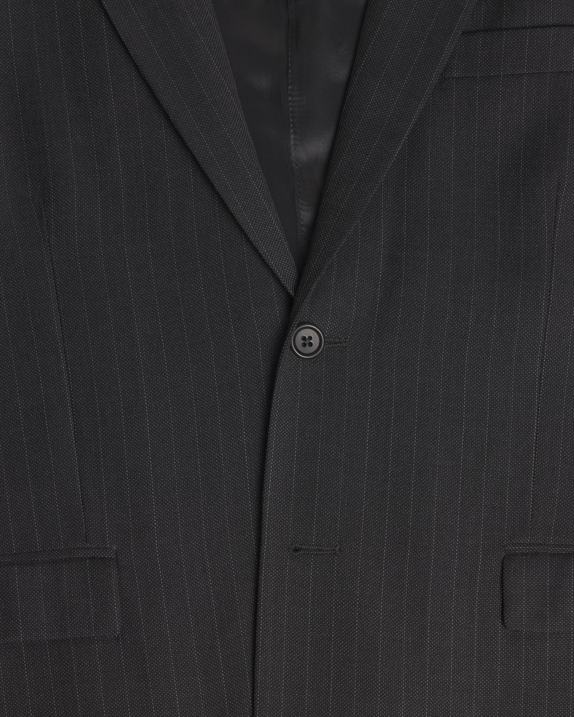 Close-up of a dark charcoal gray pinstripe suit jacket, showing the fine vertical stripes, a single button closure, and the lapel. Color: Shadow Pinstripe