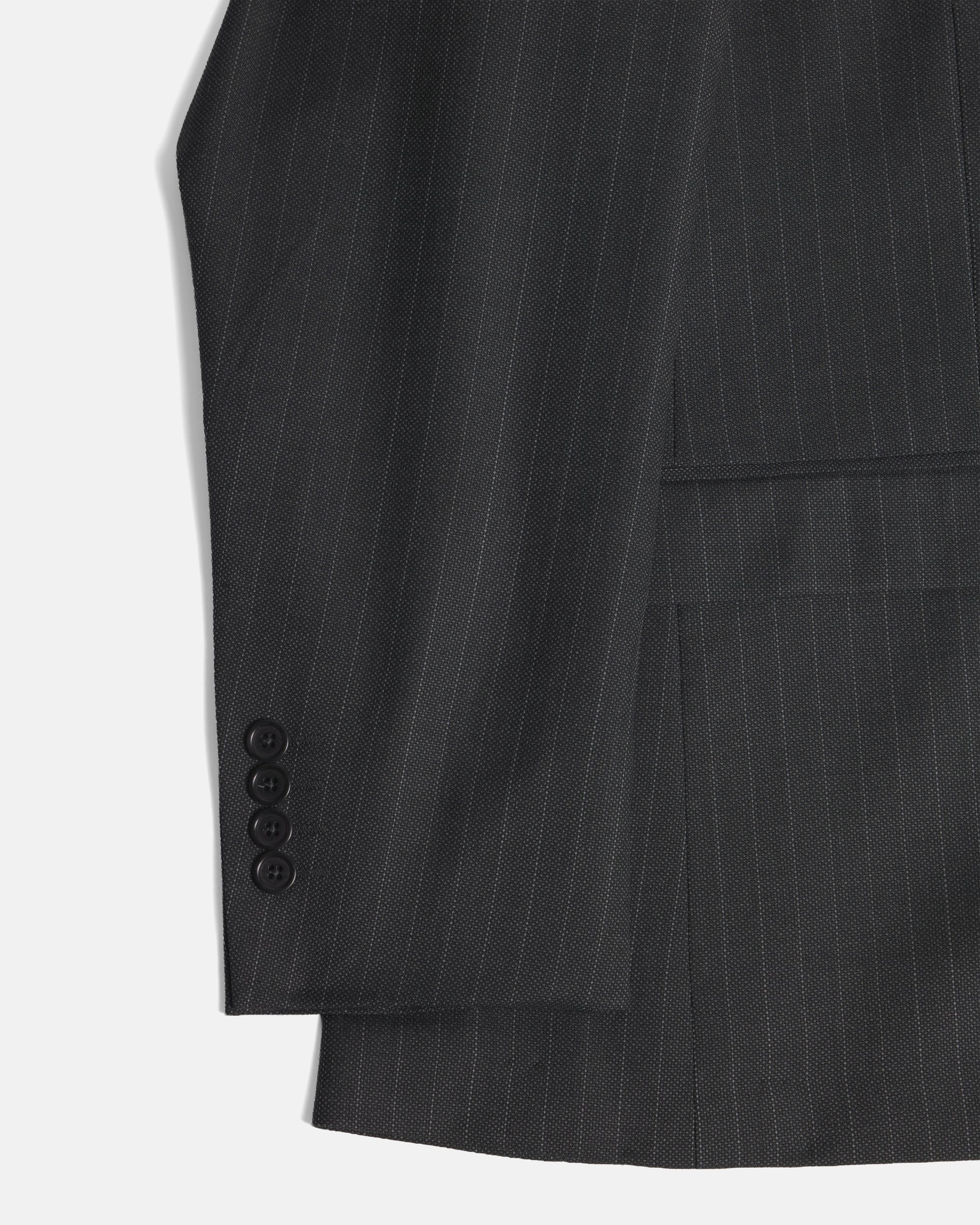 Close-up of a dark charcoal gray pinstripe suit jacket, showing the fabric texture, a buttoned cuff, and a pocket on a light gray background. Color: Shadow Pinstripe