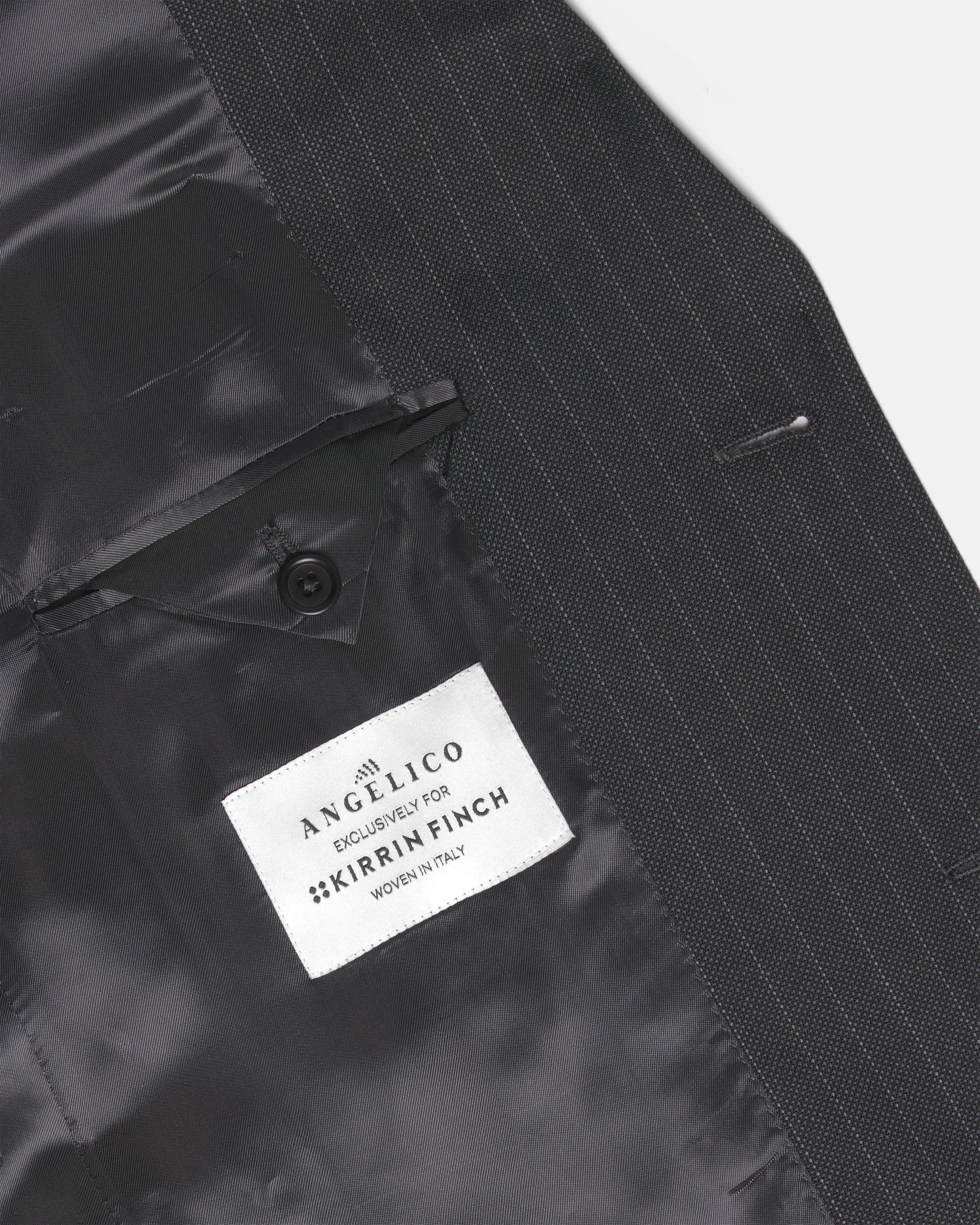 Close-up of a black pinstripe suit jacket showing the inner lining and buttoned pocket flap. Color: Shadow Pinstripe