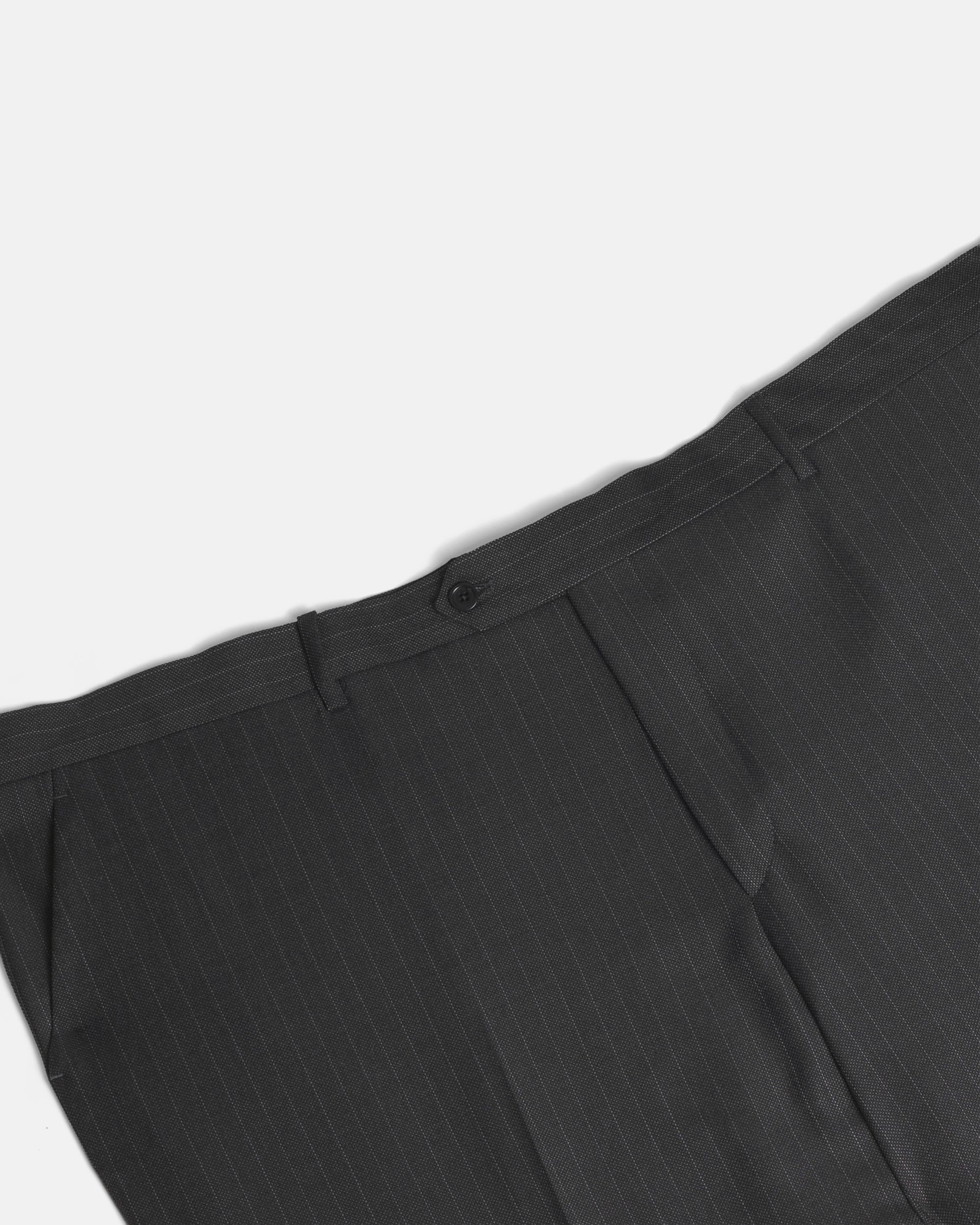 Close-up of dark charcoal gray pinstriped trousers showing the waistband, button, belt loops, and front pleats against a light gray background. Color: Shadow Pinstripe