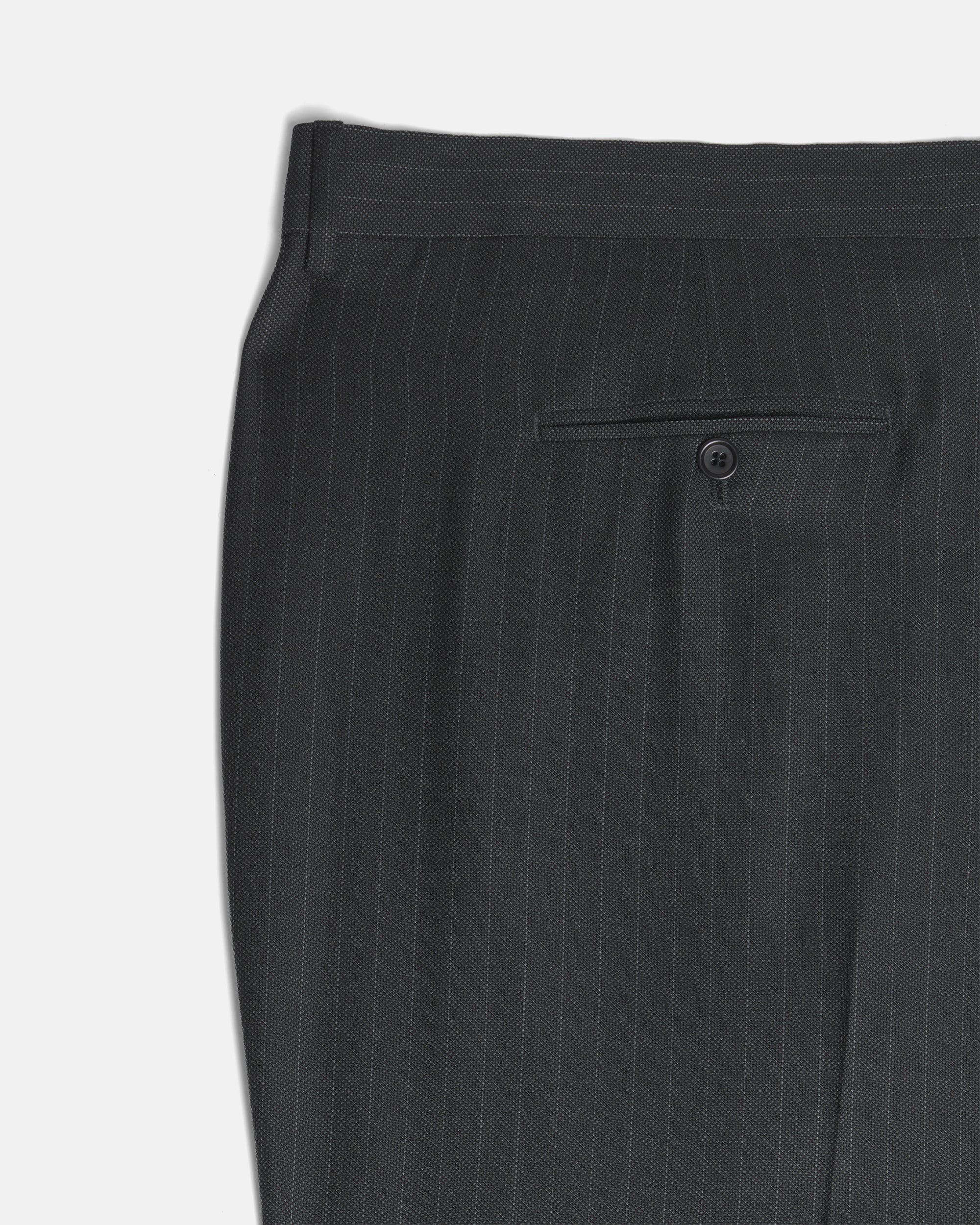 Close-up of dark charcoal gray pinstriped trousers showing the waistband and a buttoned welt pocket. Color: Shadow Pinstripe