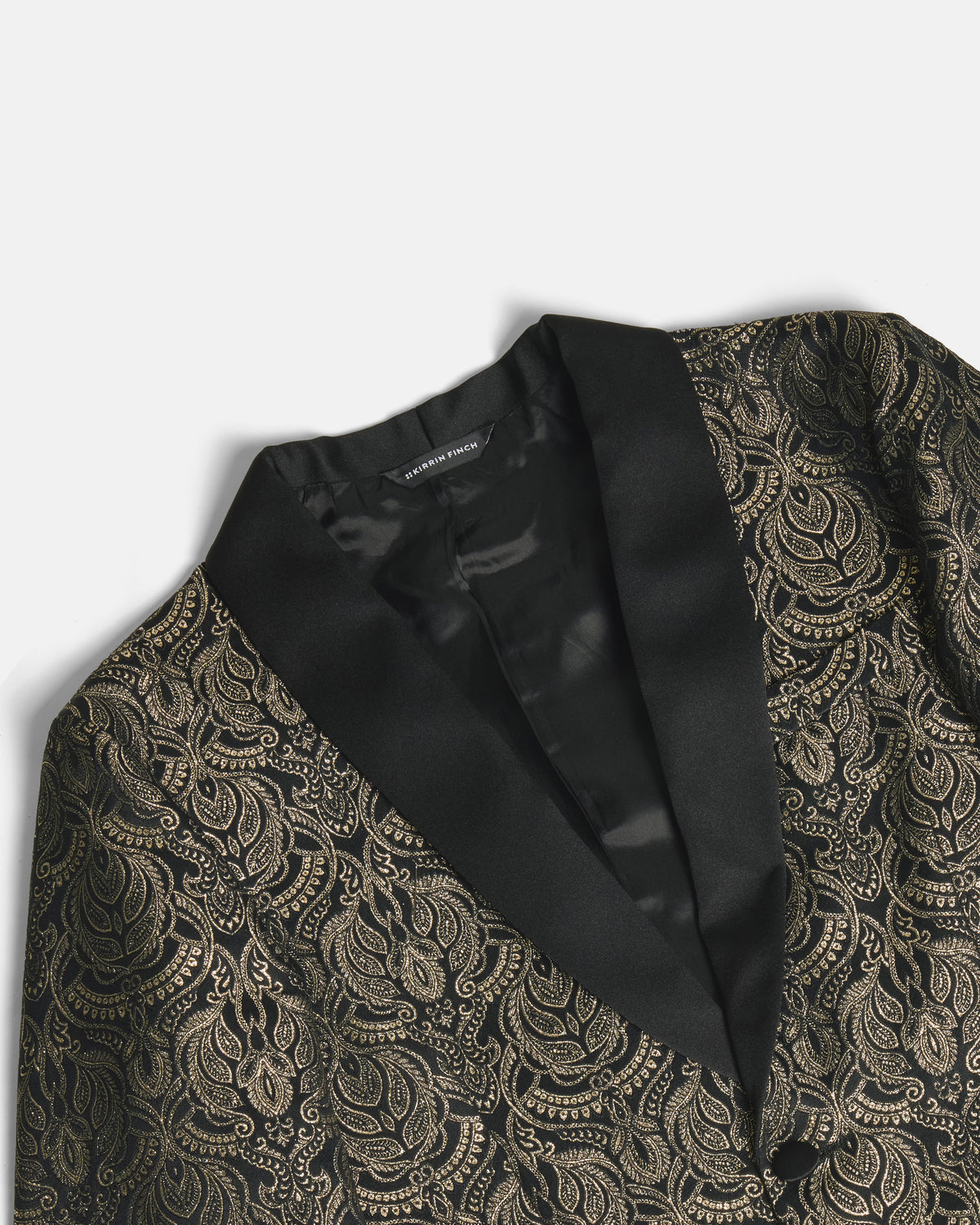 Close-up of a black and gold paisley patterned blazer with black satin lapels, showing the interior lining and collar detail. Color: Gilded Brocade