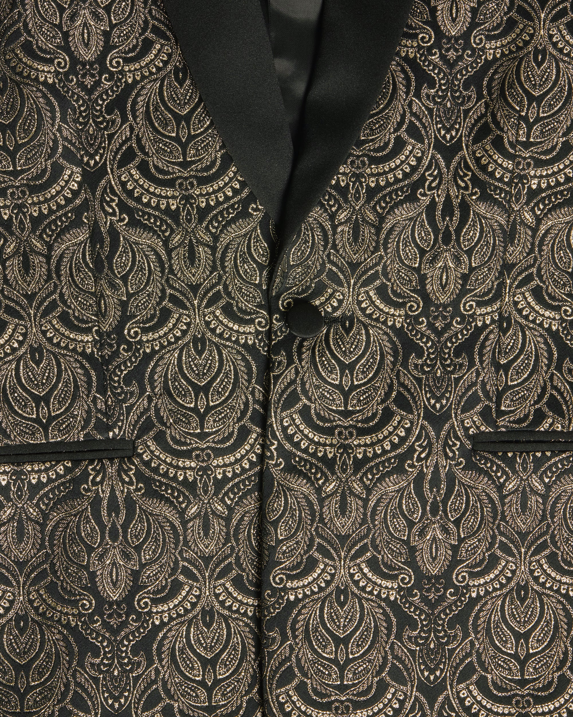Close-up of a black formal tuxedo with an ornate gold damask pattern and a black satin lapel. Color: Gilded Brocade