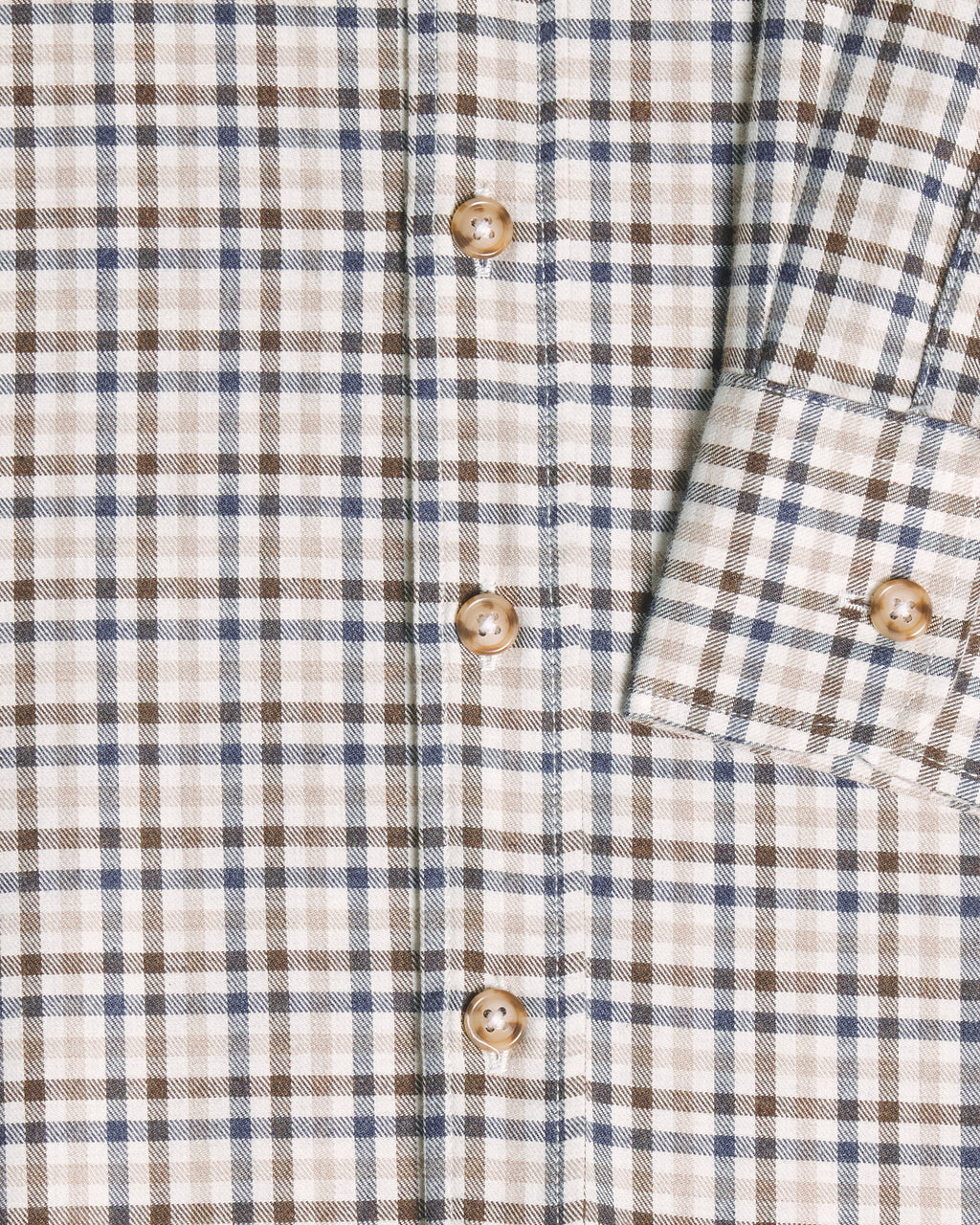 Close-up of a plaid button-up shirt with a cream base, brown and blue check lines, and brown buttons. Color: Herritage Plaid