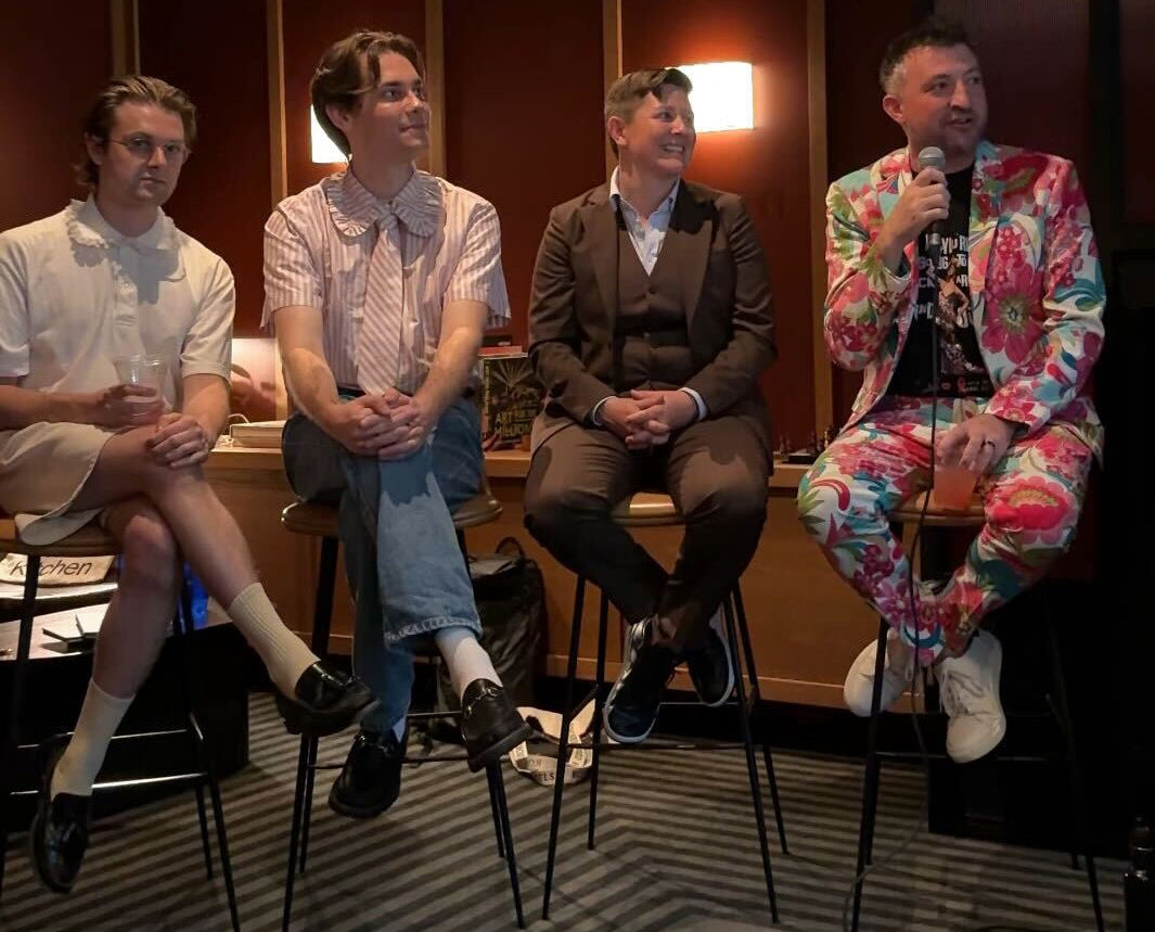 Group of people sitting on chairs in a dimly lit room with wooden paneling.