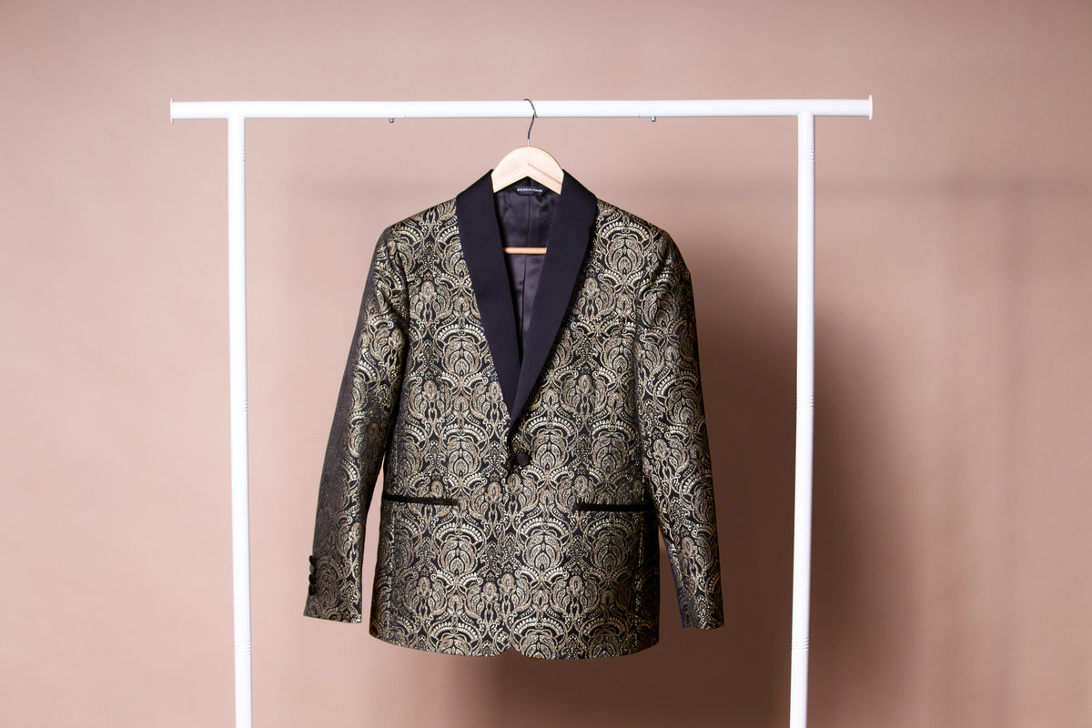 Patterned  gold and black blazer on a hanger against a plain background. Color: Gilded Brocade