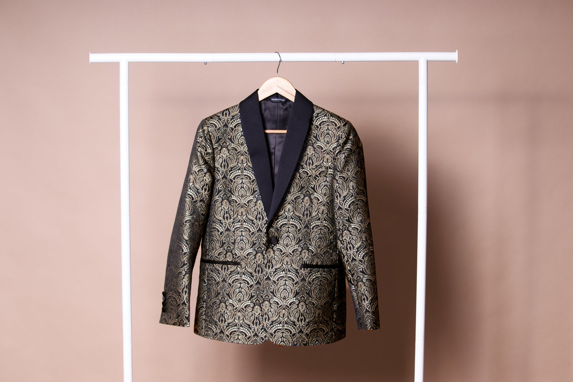 Patterned  gold and black blazer on a hanger against a plain background. Color: Gilded Brocade