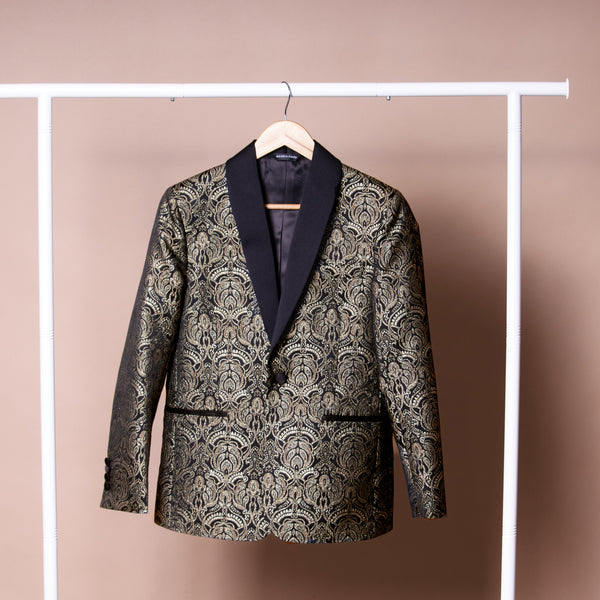 Patterned  gold and black blazer on a hanger against a plain background. Color: Gilded Brocade
