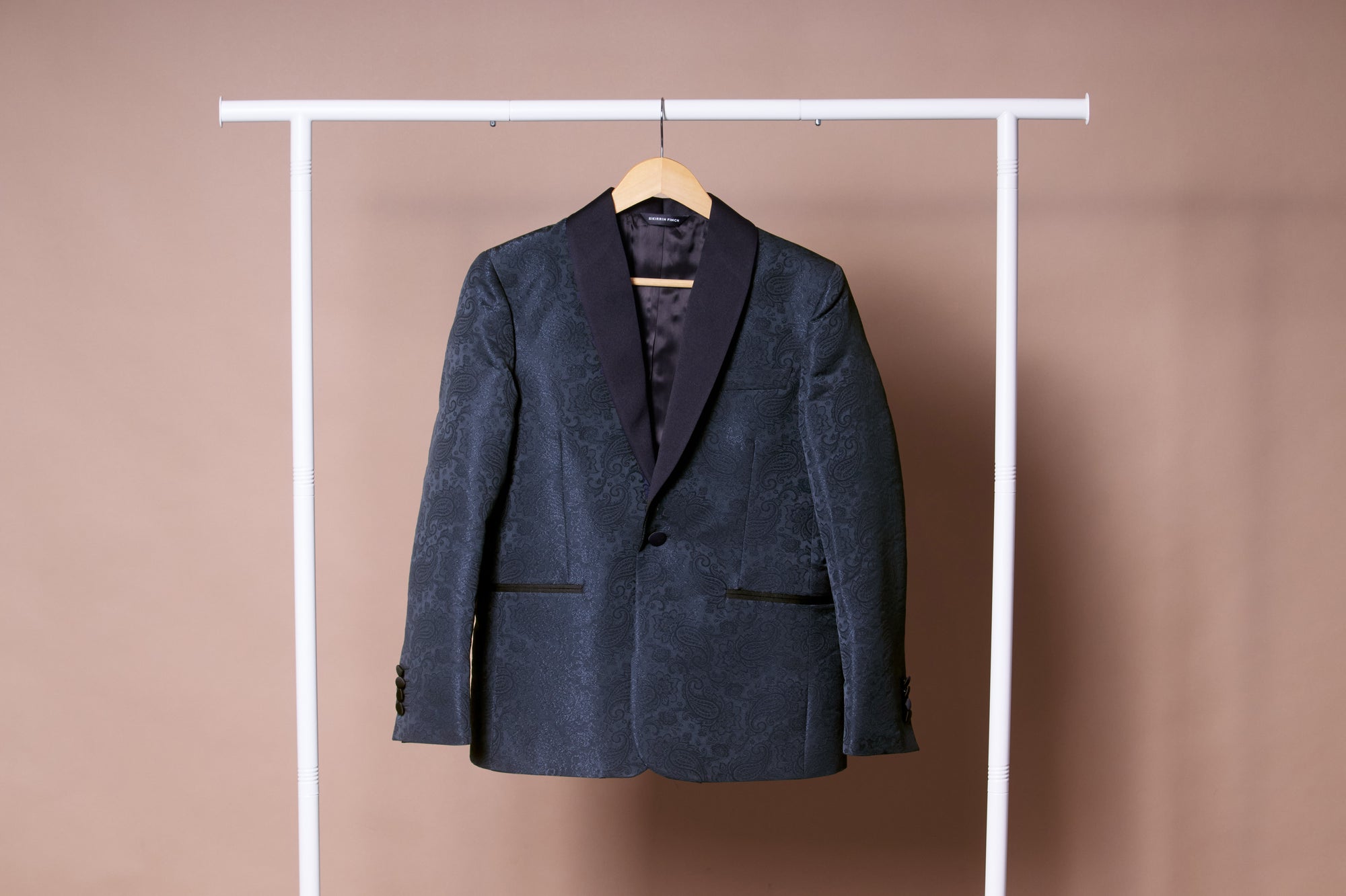 Dark blue patterned blazer on a hanger against a beige background. Color: Sapphire Brocade