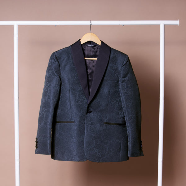 Dark blue patterned blazer on a hanger against a beige background. Color: Sapphire Brocade