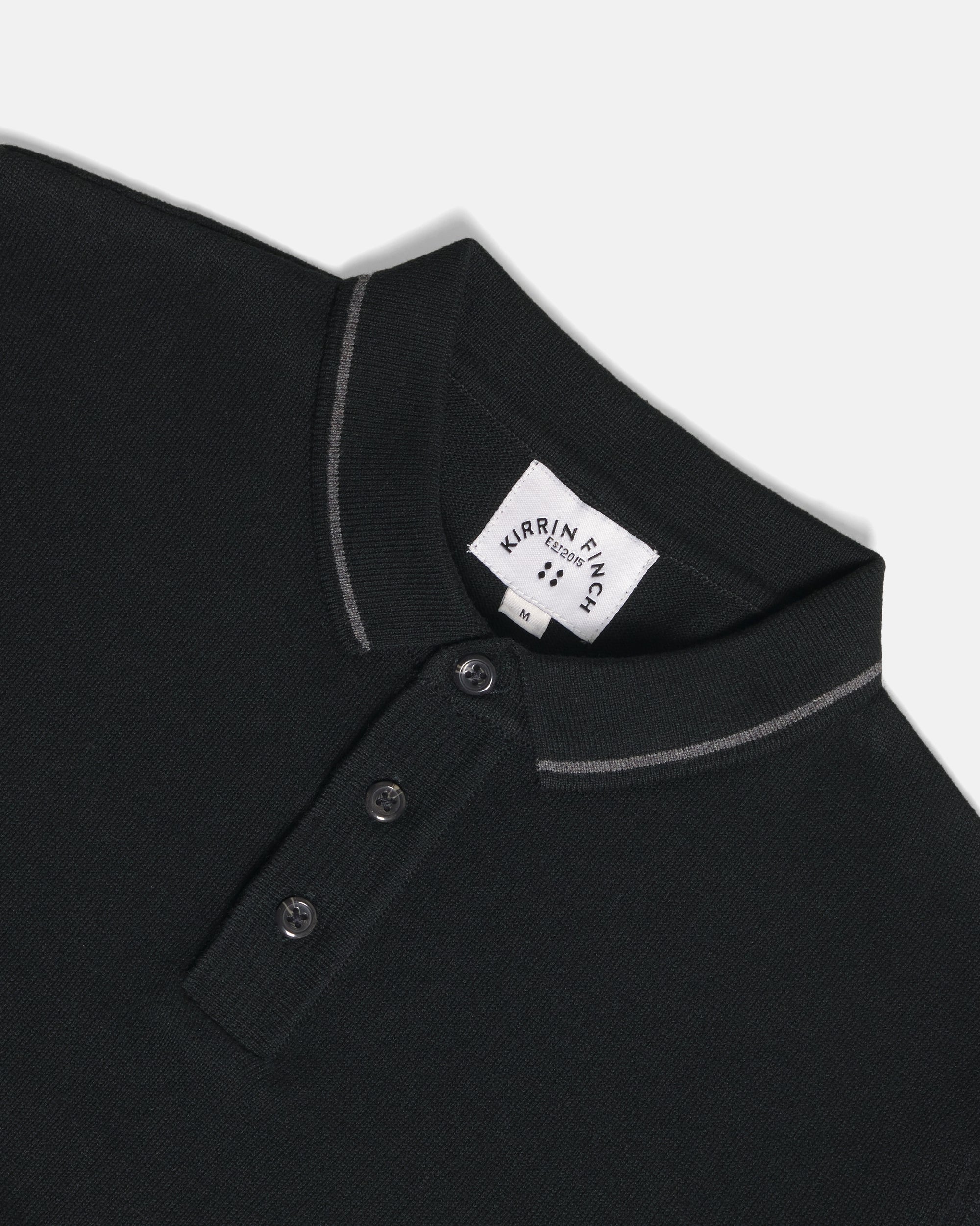 Close-up of a black polo shirt collar with  thin light piping along the collar and placket. Color: Gray Tipped