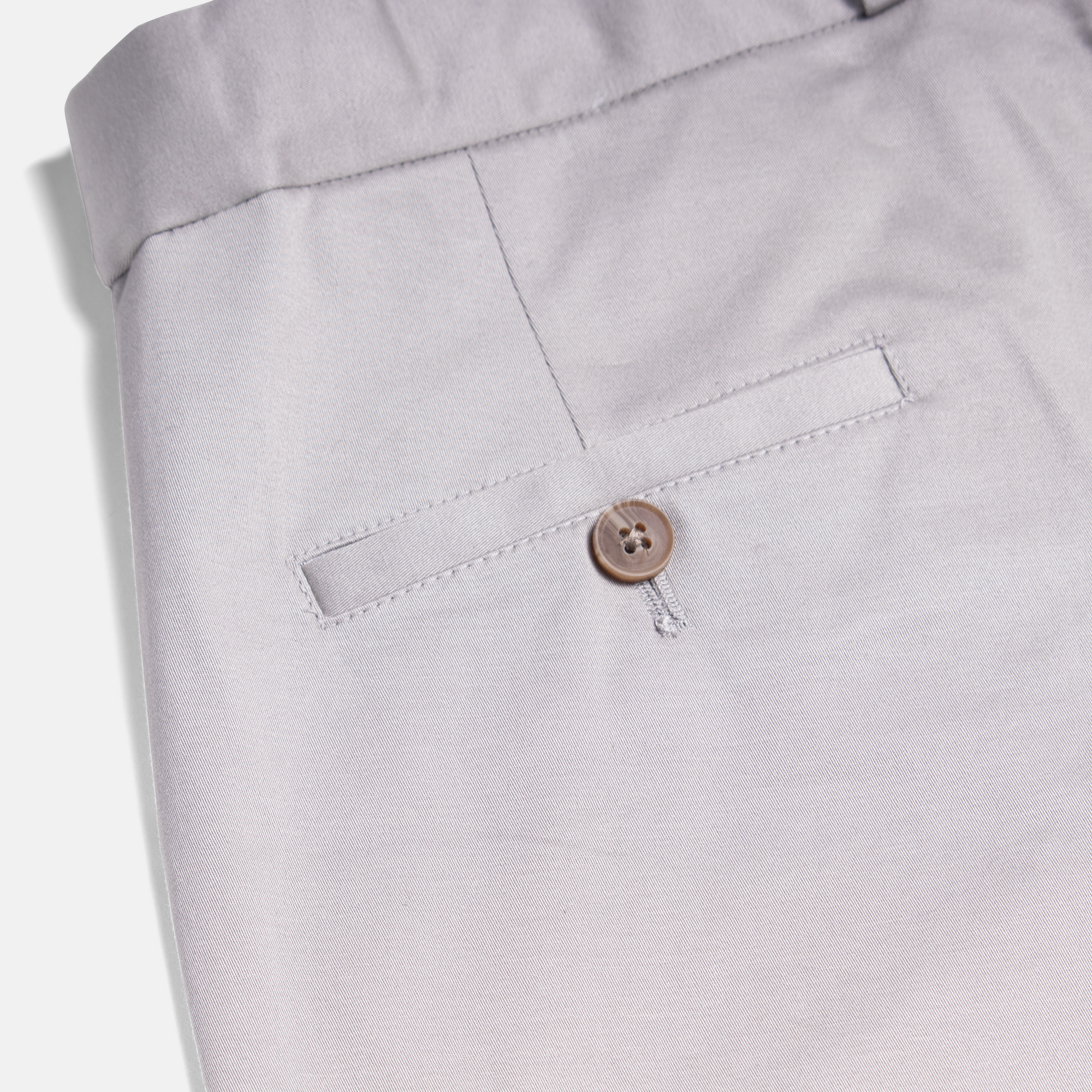 Close-up of light gray chinos showcasing back pocket button.