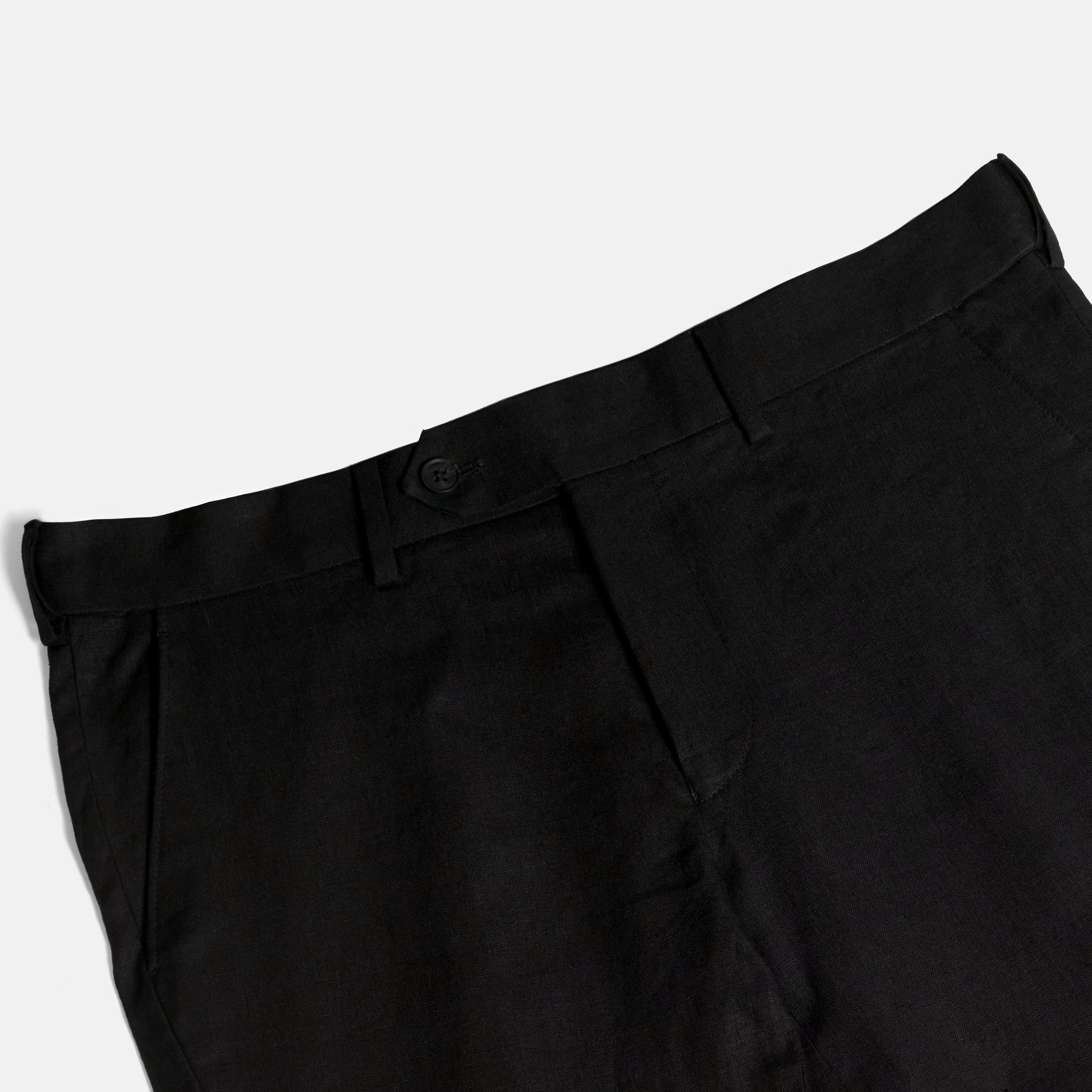Close-up of black pants on a light gray background. Color: Black