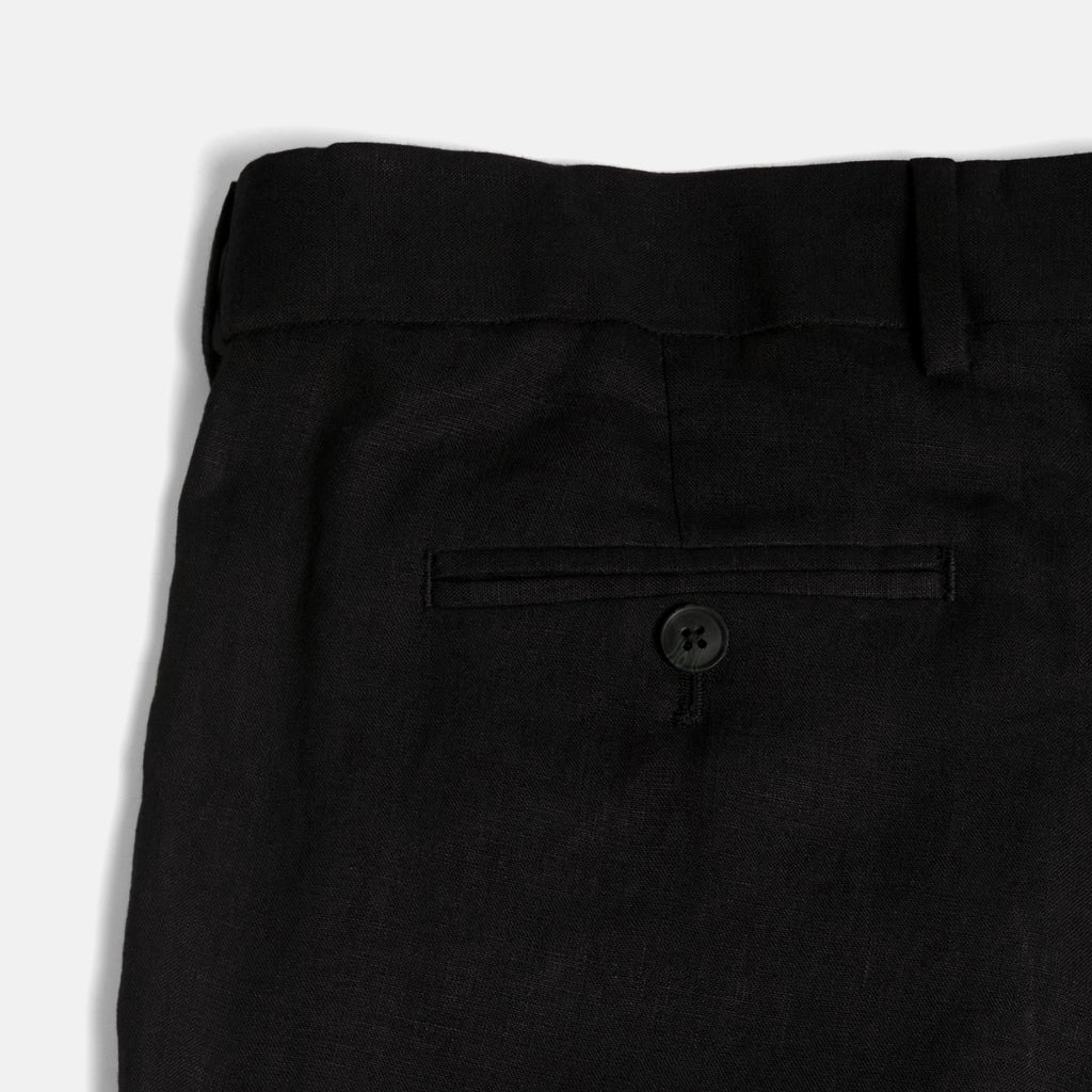 Close-up of black pants with a button on a white background. Color: Black