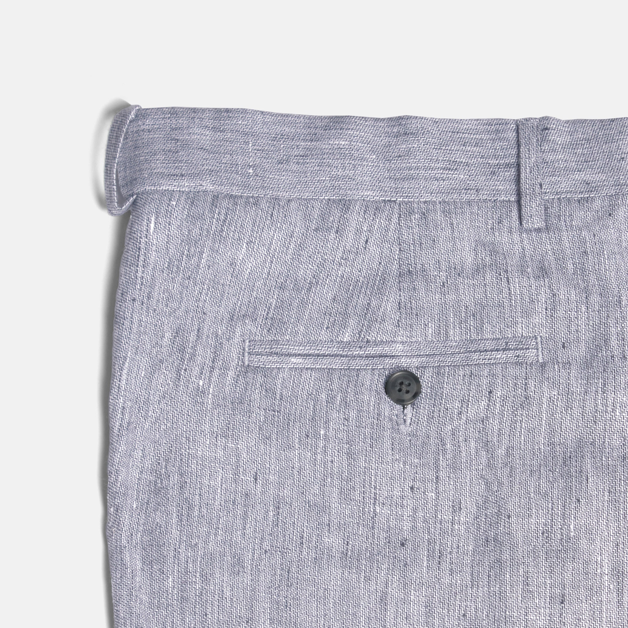 Close-up of gray pants with a button on a light gray background. Color: Graphite