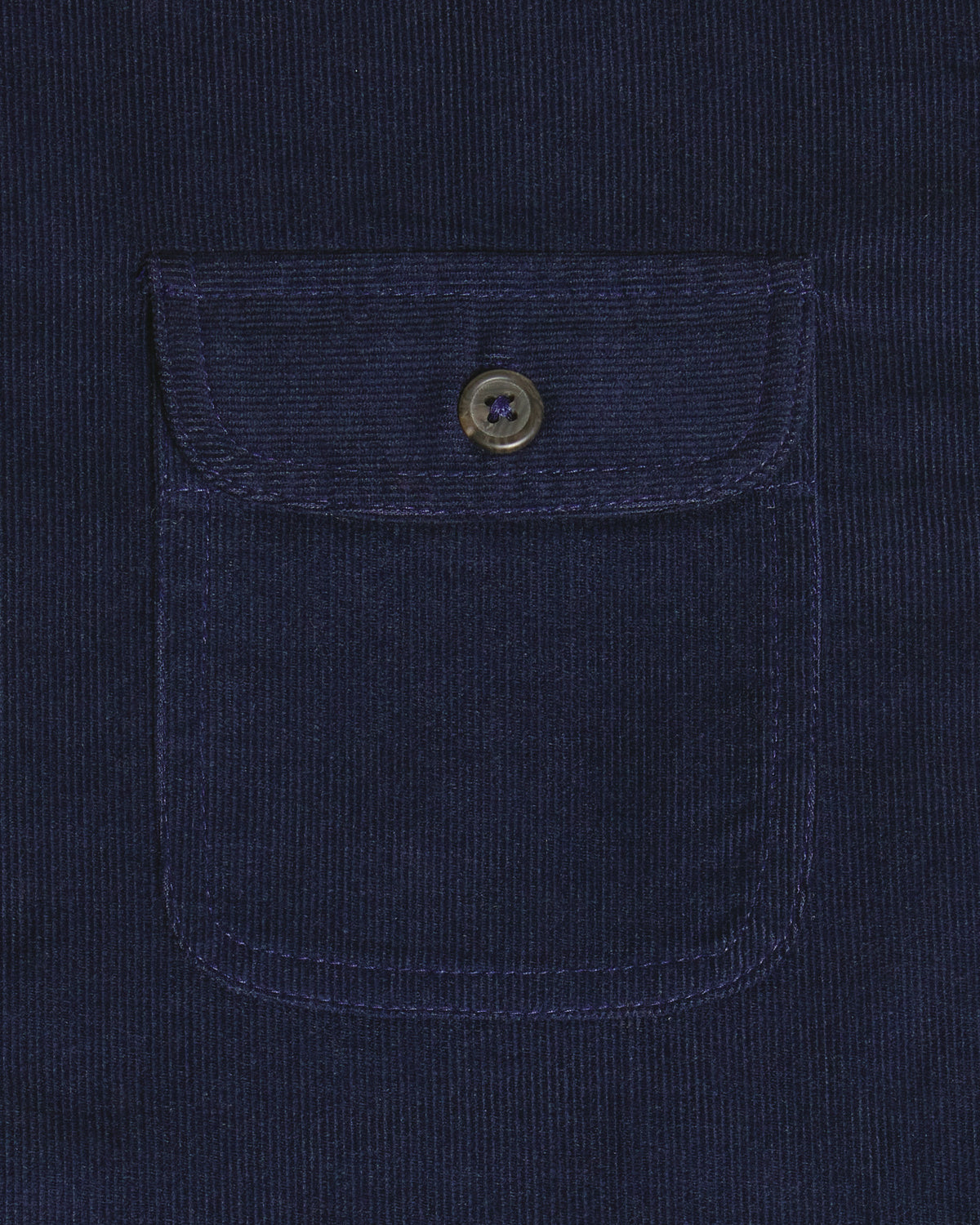 Close-up of a dark navy corduroy pocket with a buttoned flap on a matching navy corduroy garment. Color: Maritime Blue