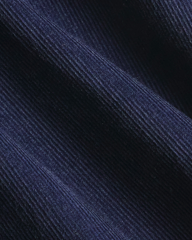 A close-up of dark navy blue corduroy fabric with its characteristic ribbed texture and soft folds. Color: Maritime Blue