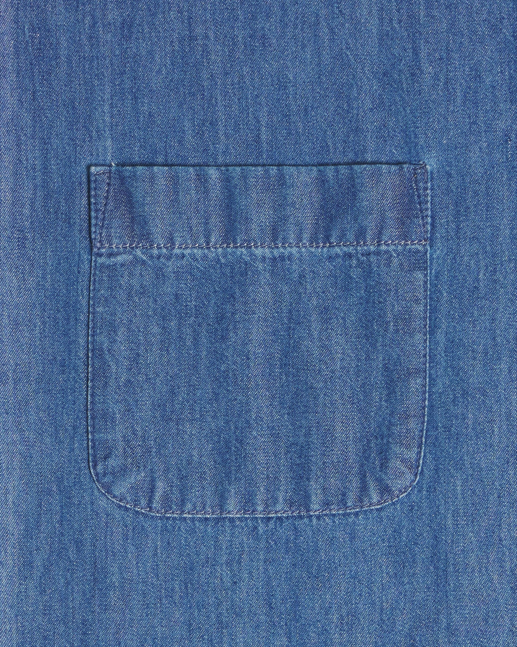 A close-up of a blue denim fabric with a single front patch pocket and visible stitching. Color: Medium Wash Denim