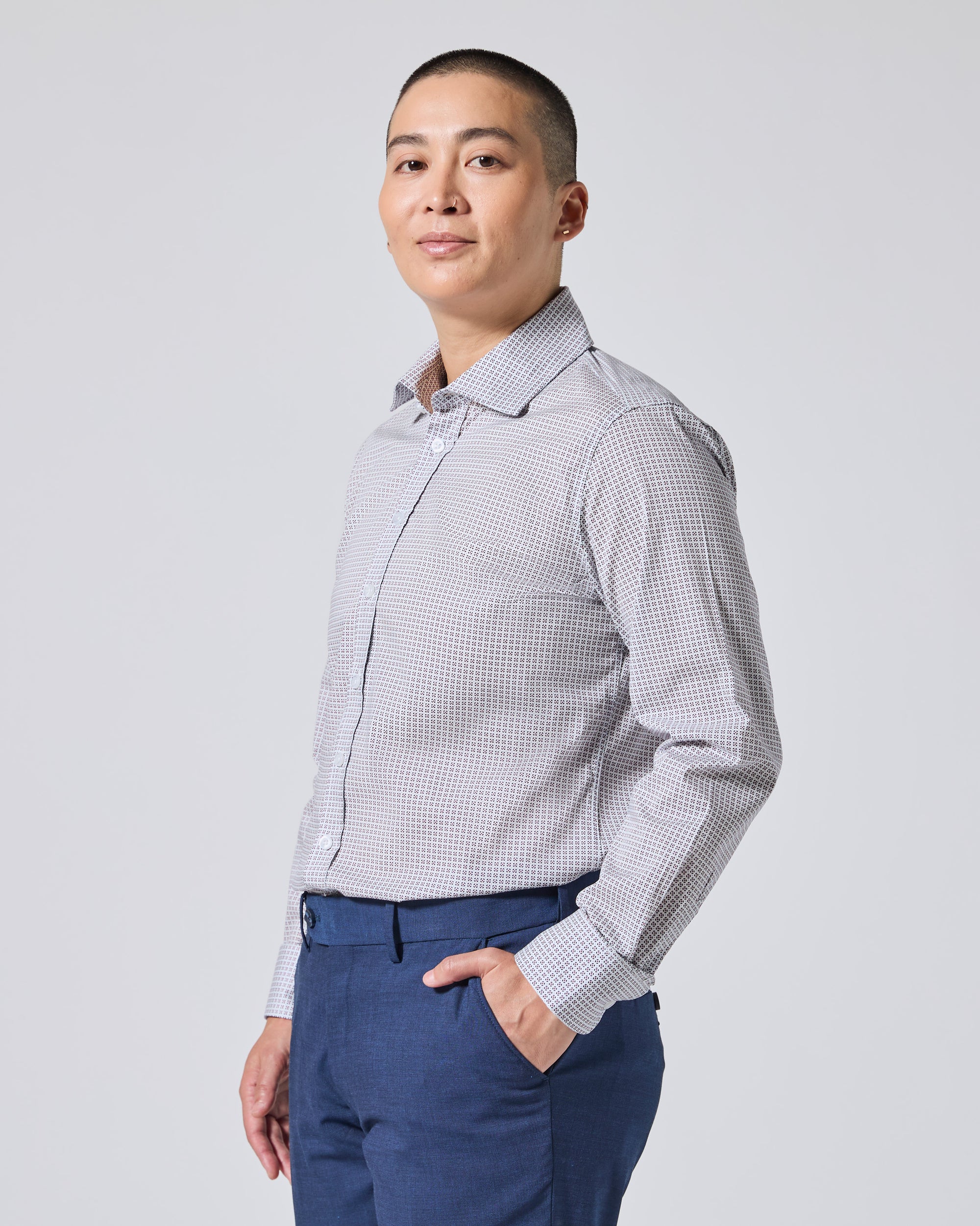 Model wearing a light gray and white  long-sleeve button-down shirt paired with navy blue trousers, standing against a solid light gray background. Color: Navy Rosette