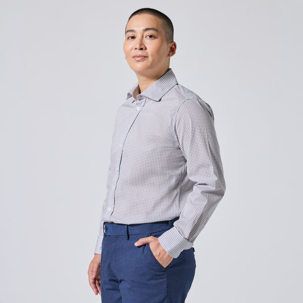 Model wearing a light gray and white  long-sleeve button-down shirt paired with navy blue trousers, standing against a solid light gray background. Color: Navy Rosette