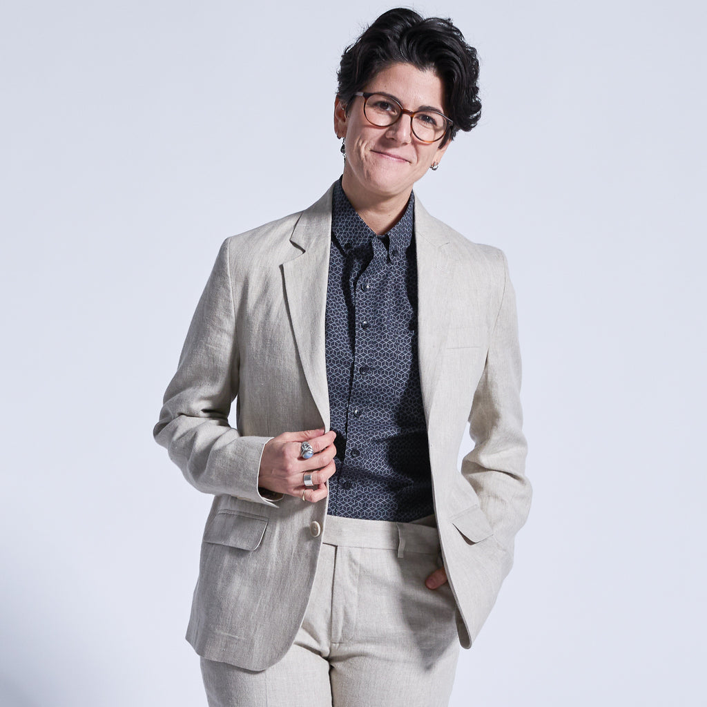 Model wearing glasses and a linen blazer over a black patterned shirt  Color: Oat