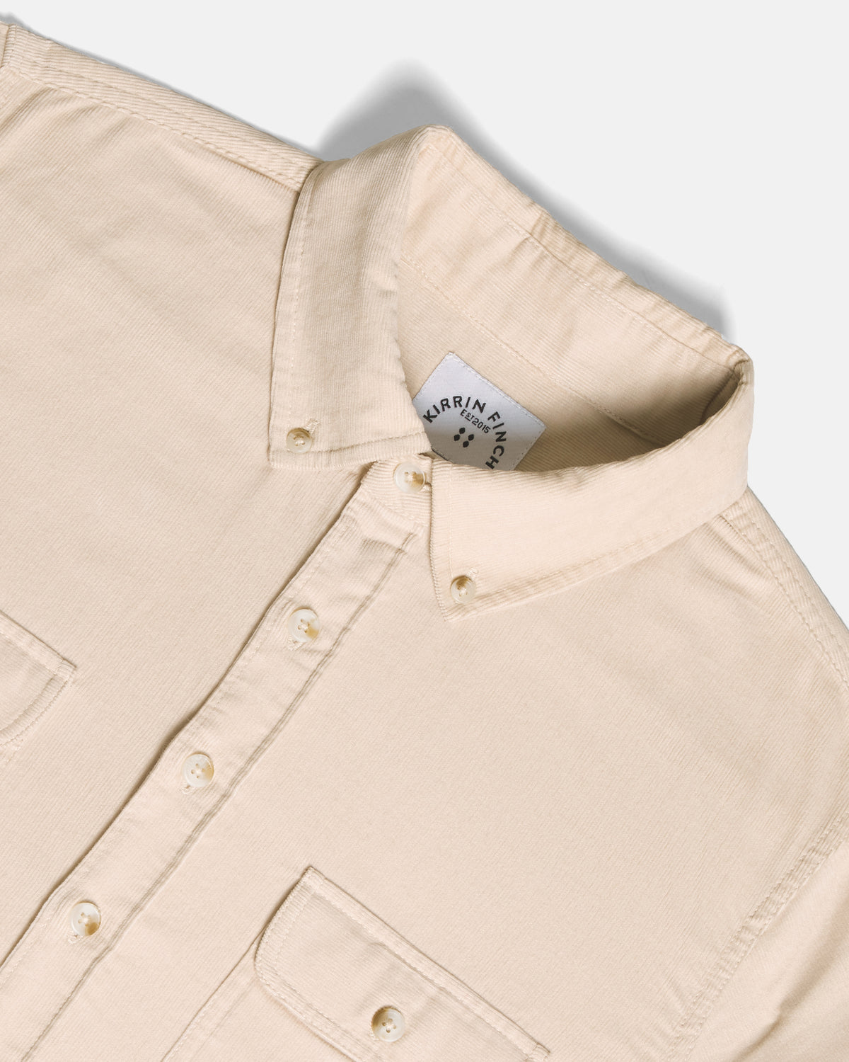 Close-up of a light beige button-down shirt collar, set against a clean off-white background.  Color: Oatmeal