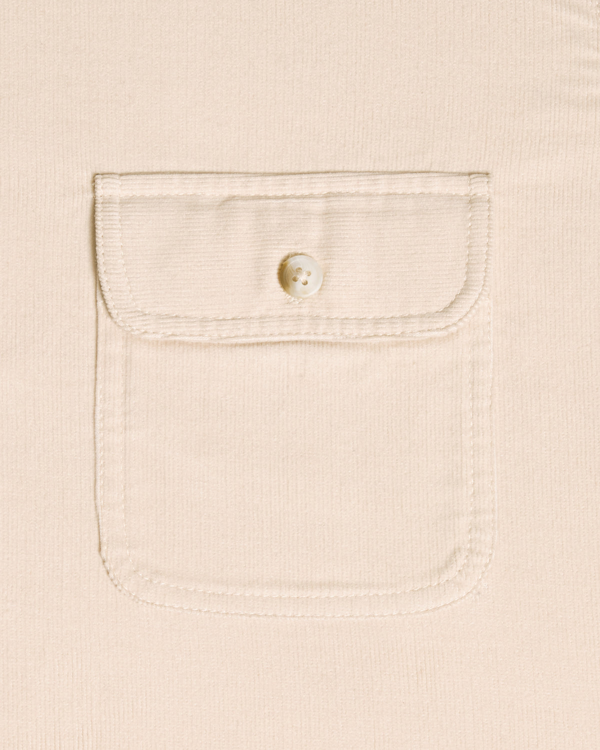 Close-up of a cream-colored textured fabric with a single buttoned flap pocket.  Color: Oatmeal