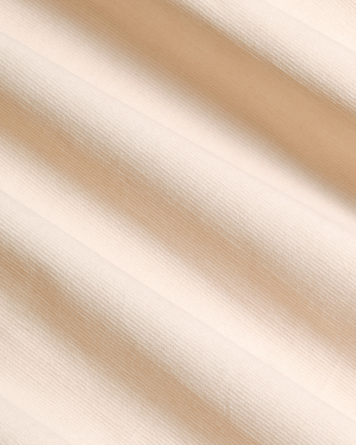 A close-up of a light beige fabric with a fine textured weave, showing soft diagonal shadows cast across the surface.  Color: Oatmeal