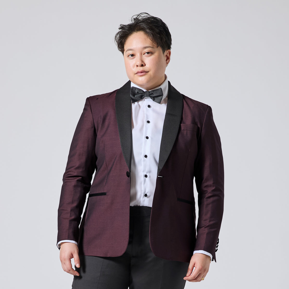 Model wearing a Deep burgundy tuxedo blazer over a white shirt with black buttons and a matching bow tie. Color: Deep Oxblood