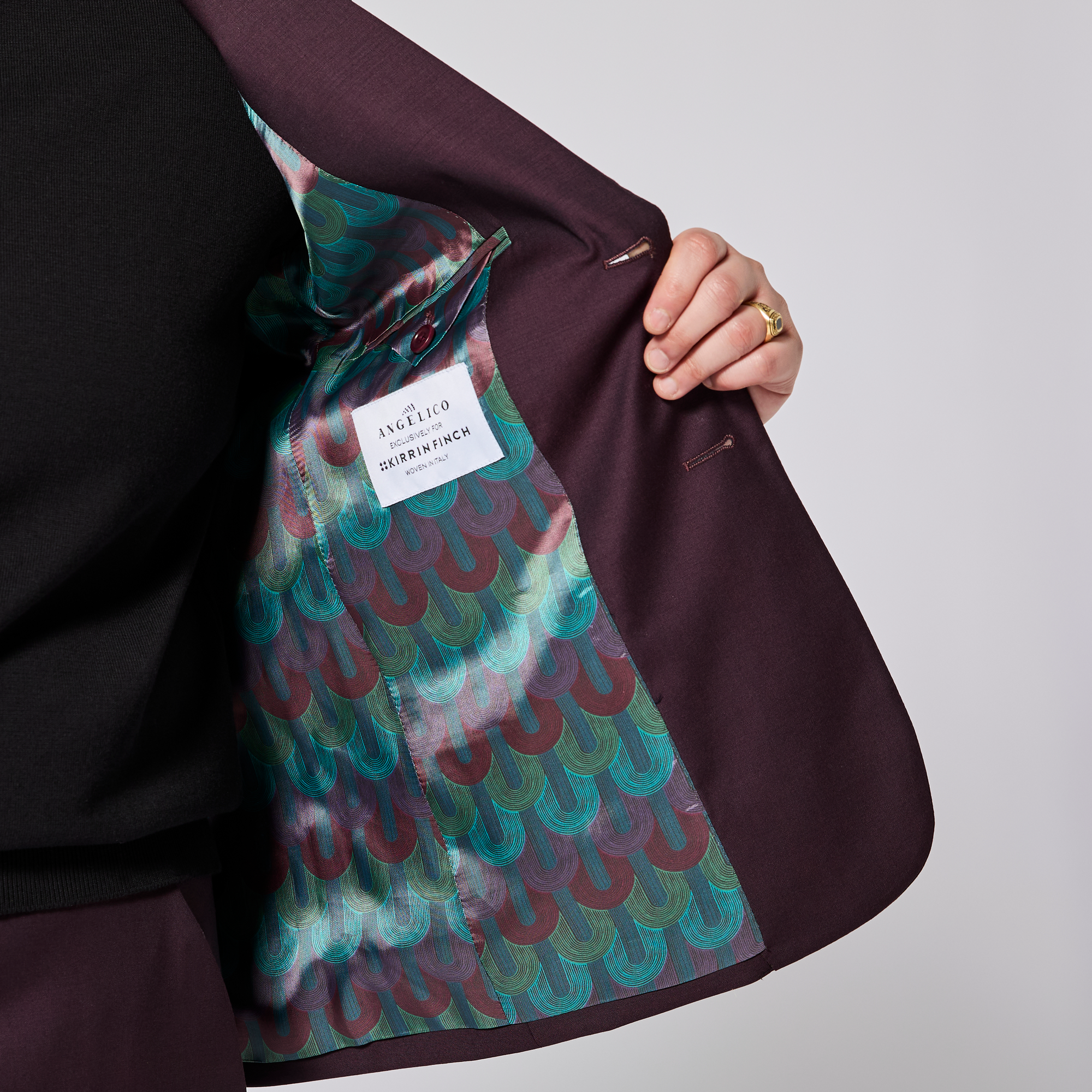 Close-up of a suit with a patterned lining and a visible Kirrin Finch label on a plain background. Color: Deep Oxblood
