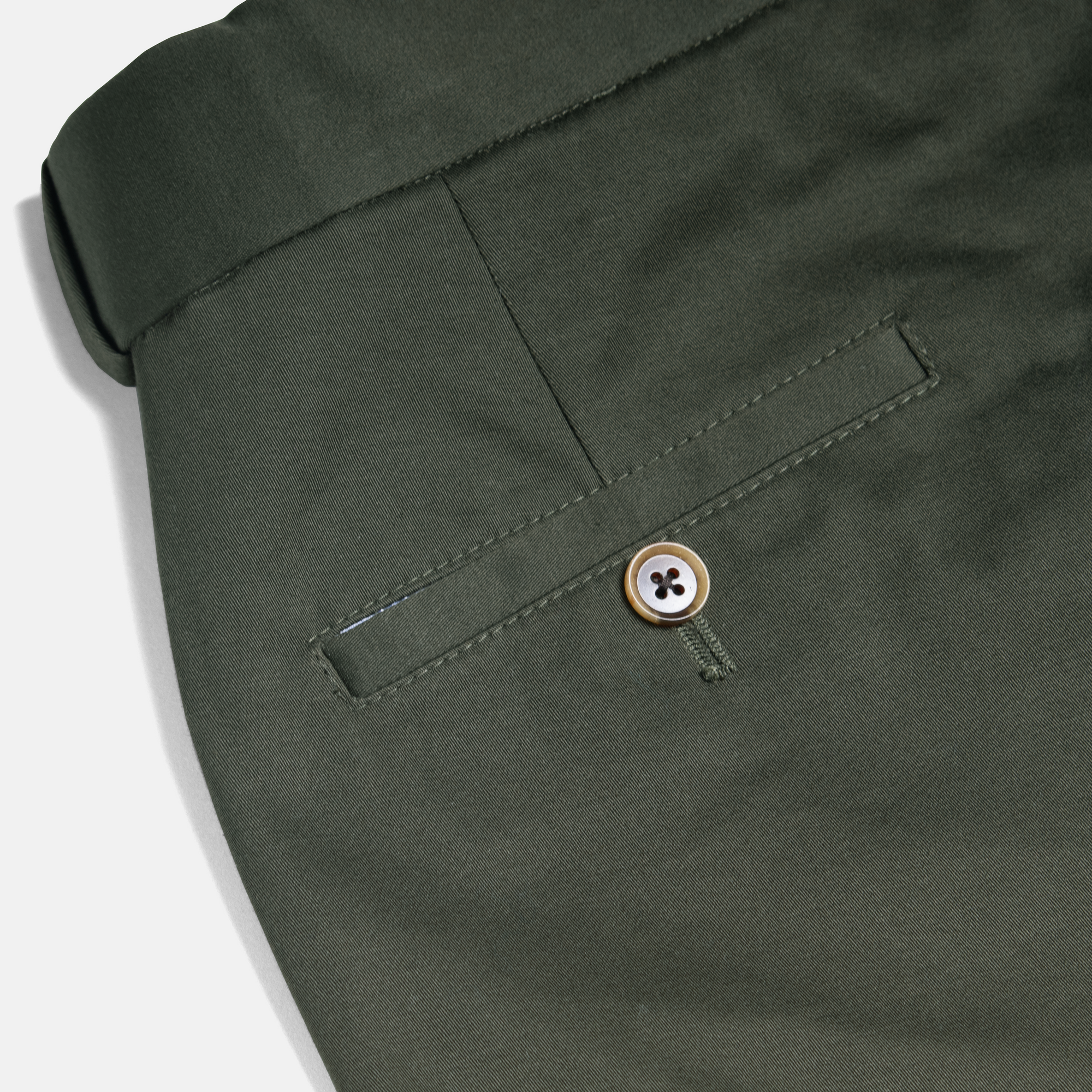 Close-up of olive chinos showcasing back pocket button.