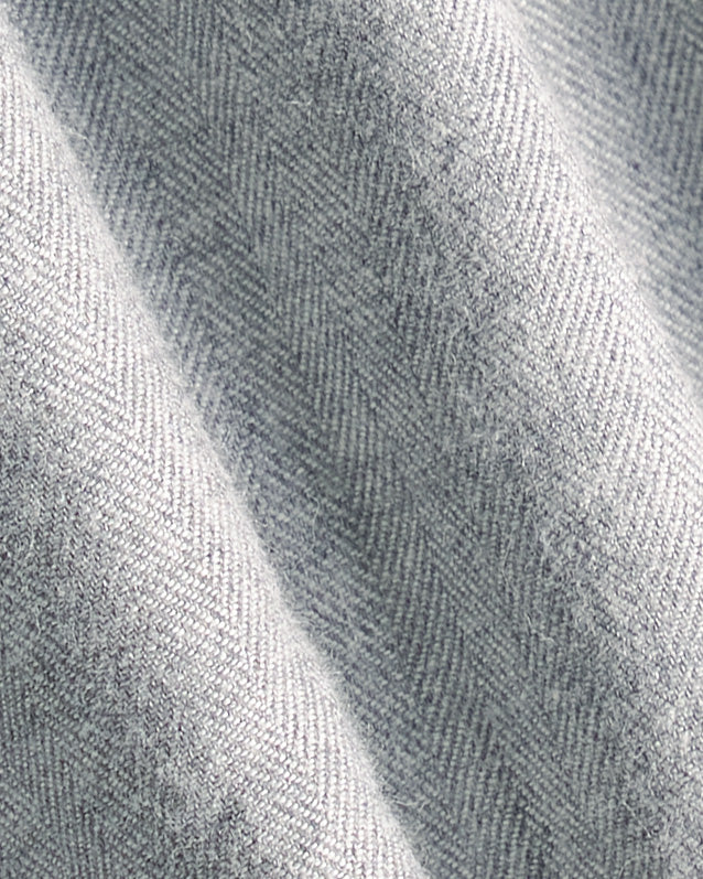A close-up of light gray herringbone fabric with a soft woven texture and gentle folds. Color: Pewter Herringbone