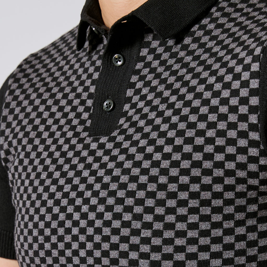 Close-up of a black and gray checkered knit polo shirt with a black collar and two dark buttons. Color: Shadow Checker