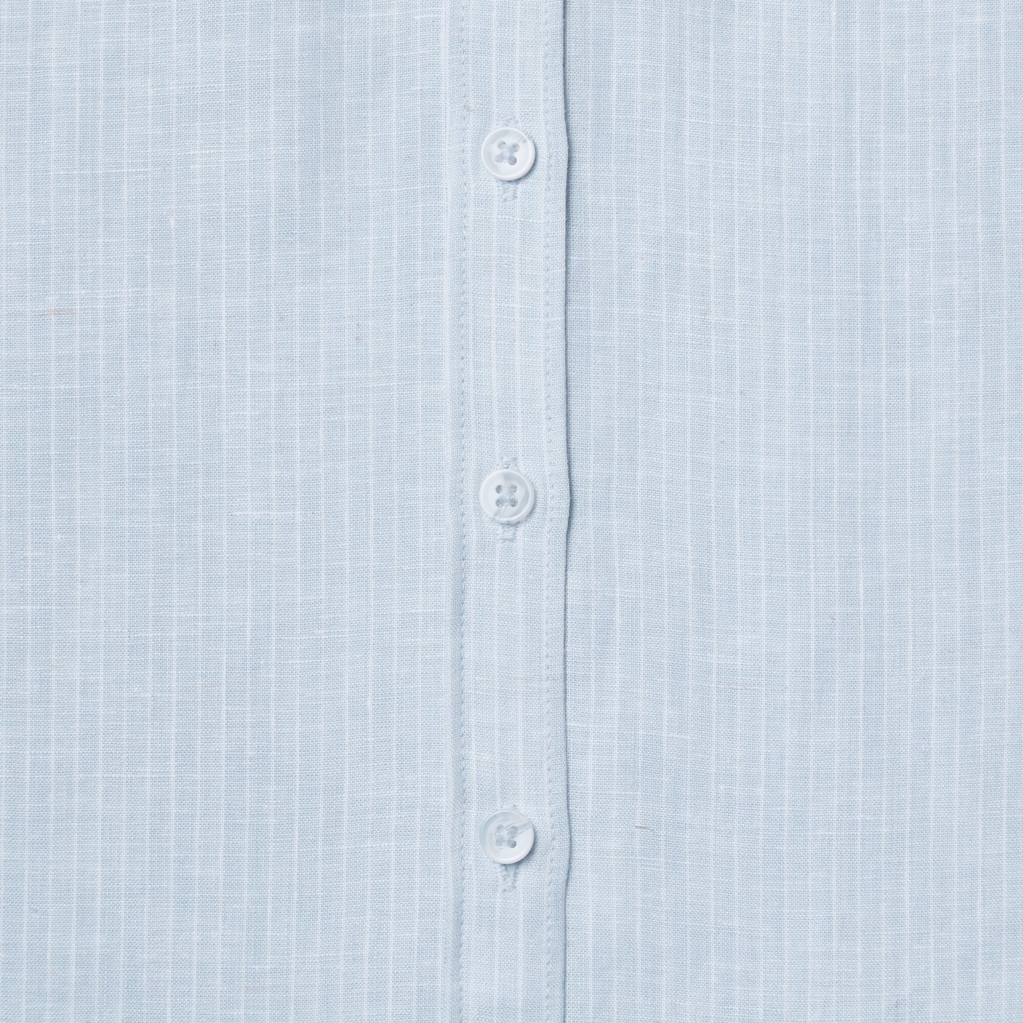 Close-up of a light blue shirt with buttons. Color: Curacao
