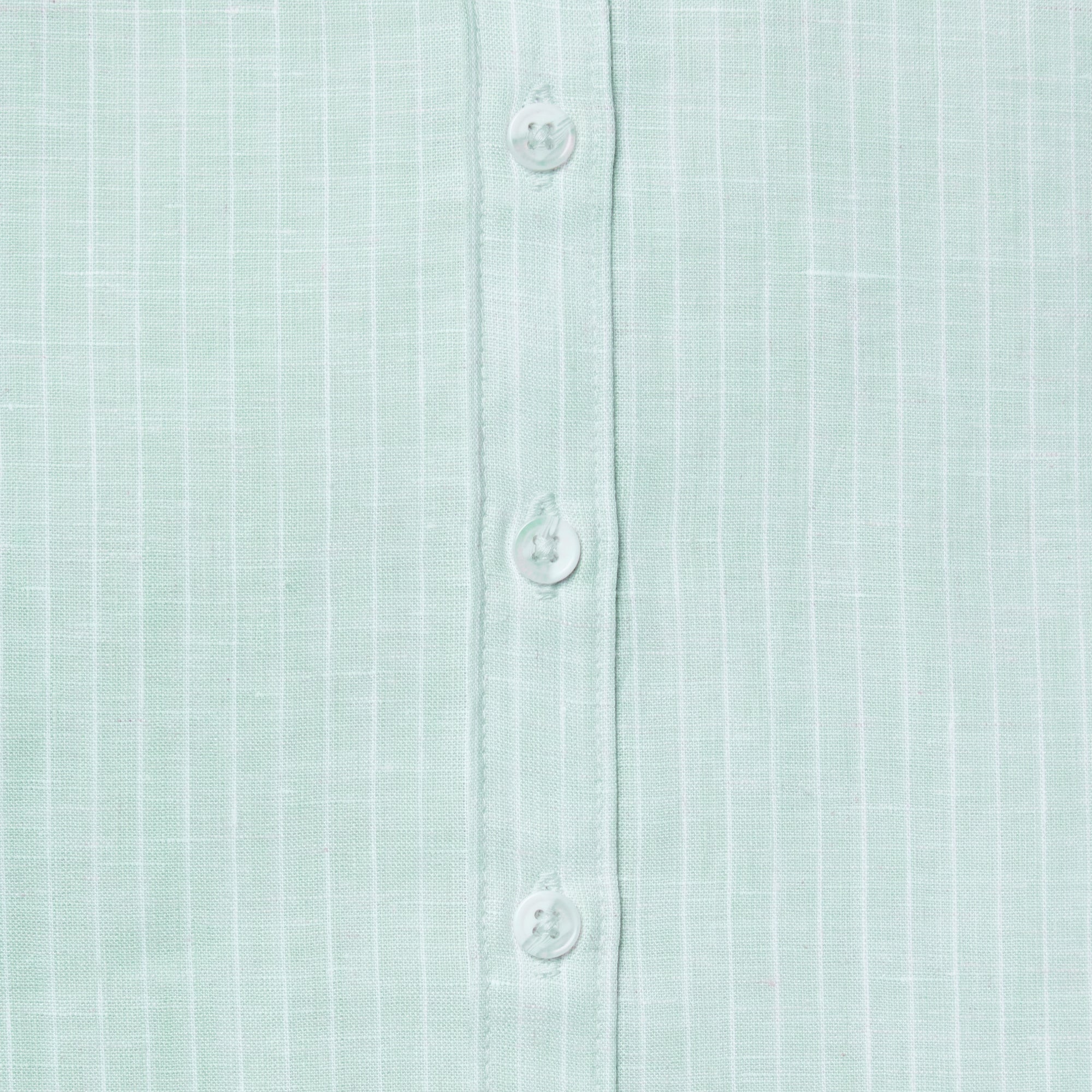 Close-up of a light green textured shirt with buttons. Color: Mojito